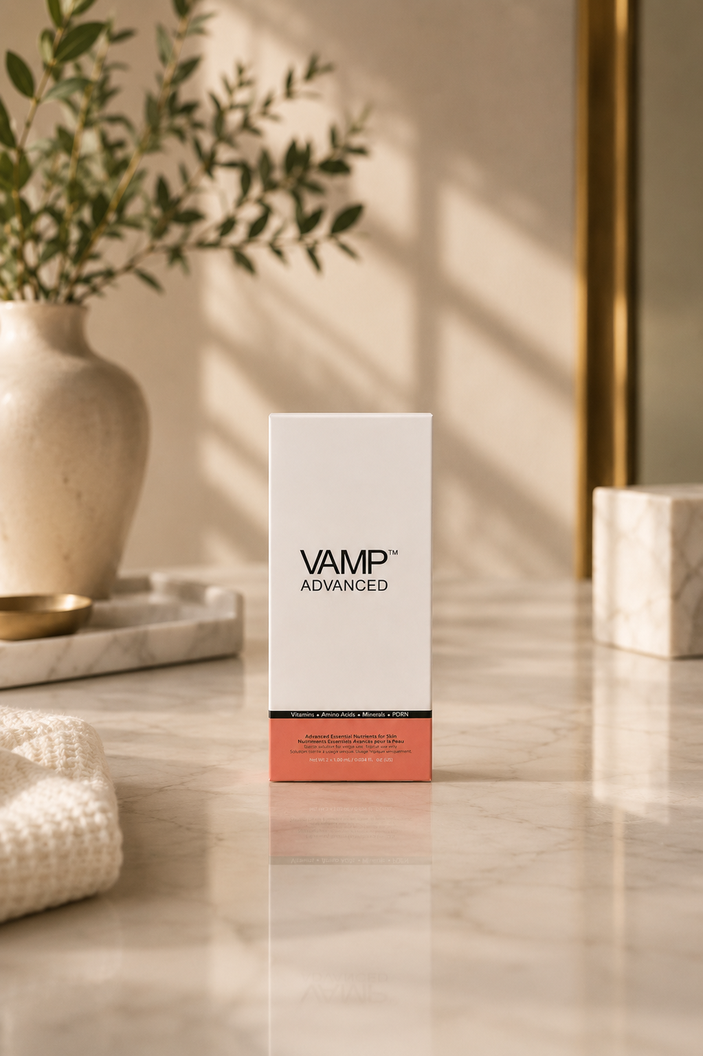 A white box labeled 'VAMP™ ADVANCED' on a marble surface with a decorative vase with greenery, a small bowl, and marble blocks in the background, illuminated by natural light.