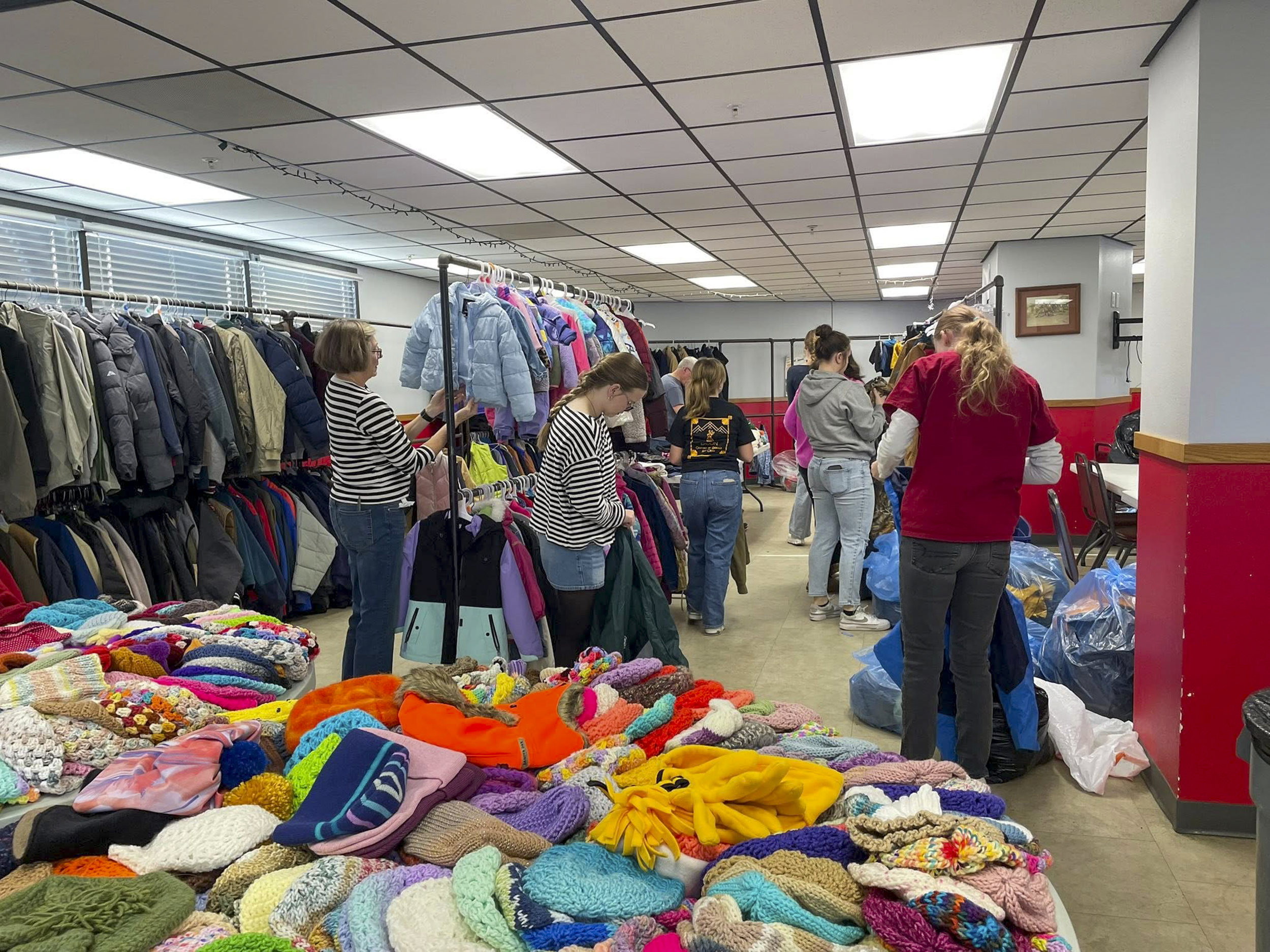 Volunteers help sort coats at a thrift store.