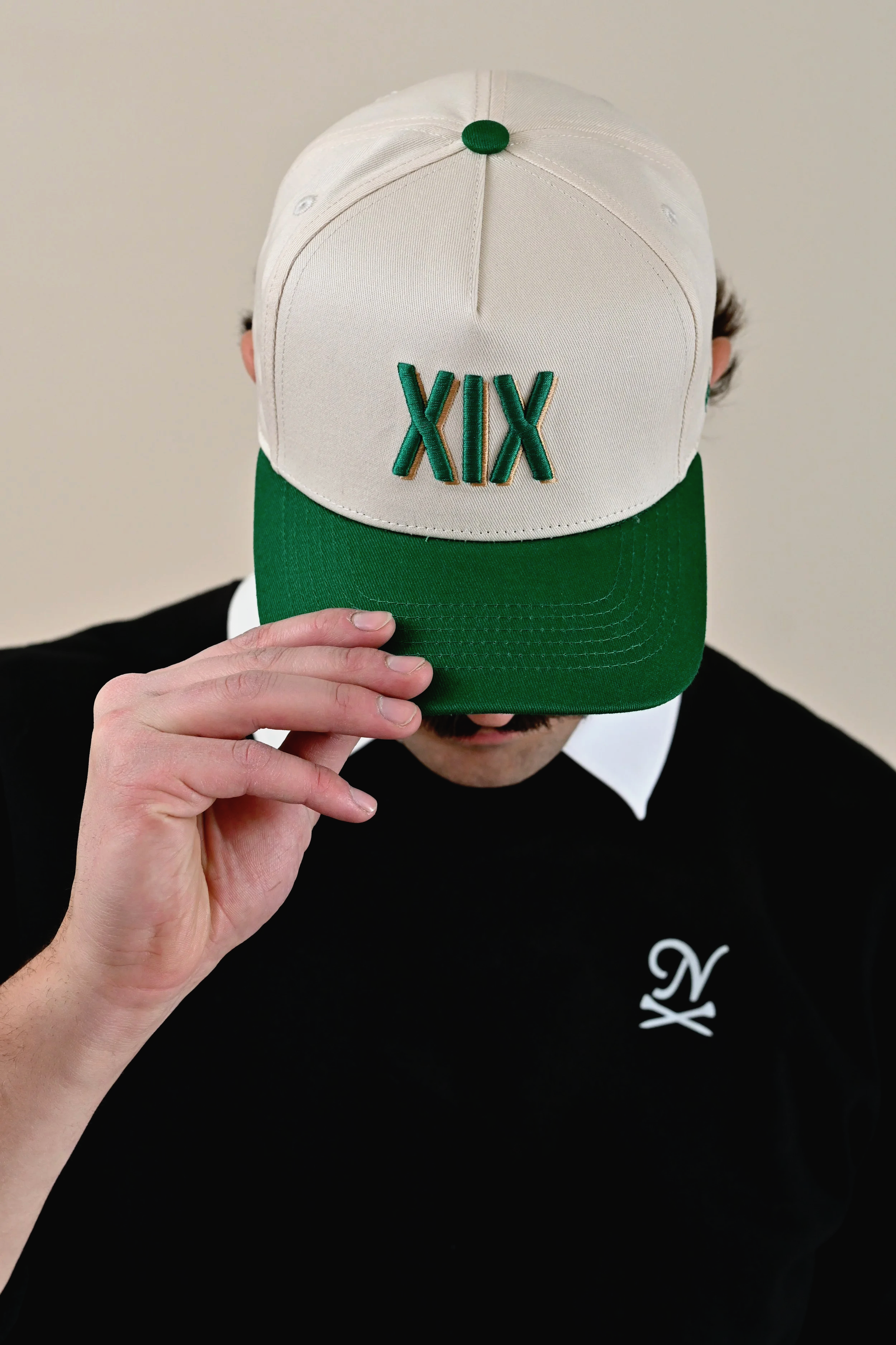 Man wearing XIX (Nineteenth Hole) hat  in green and cream