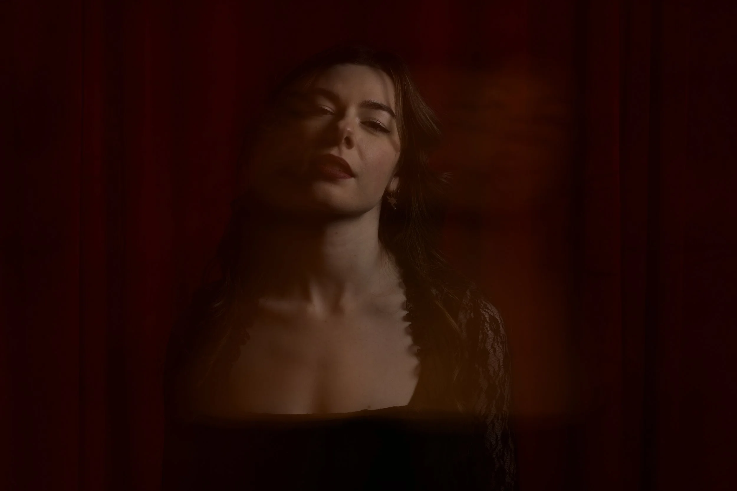 close up of woman in a black dress infron of a red curtain with slow shutter speed