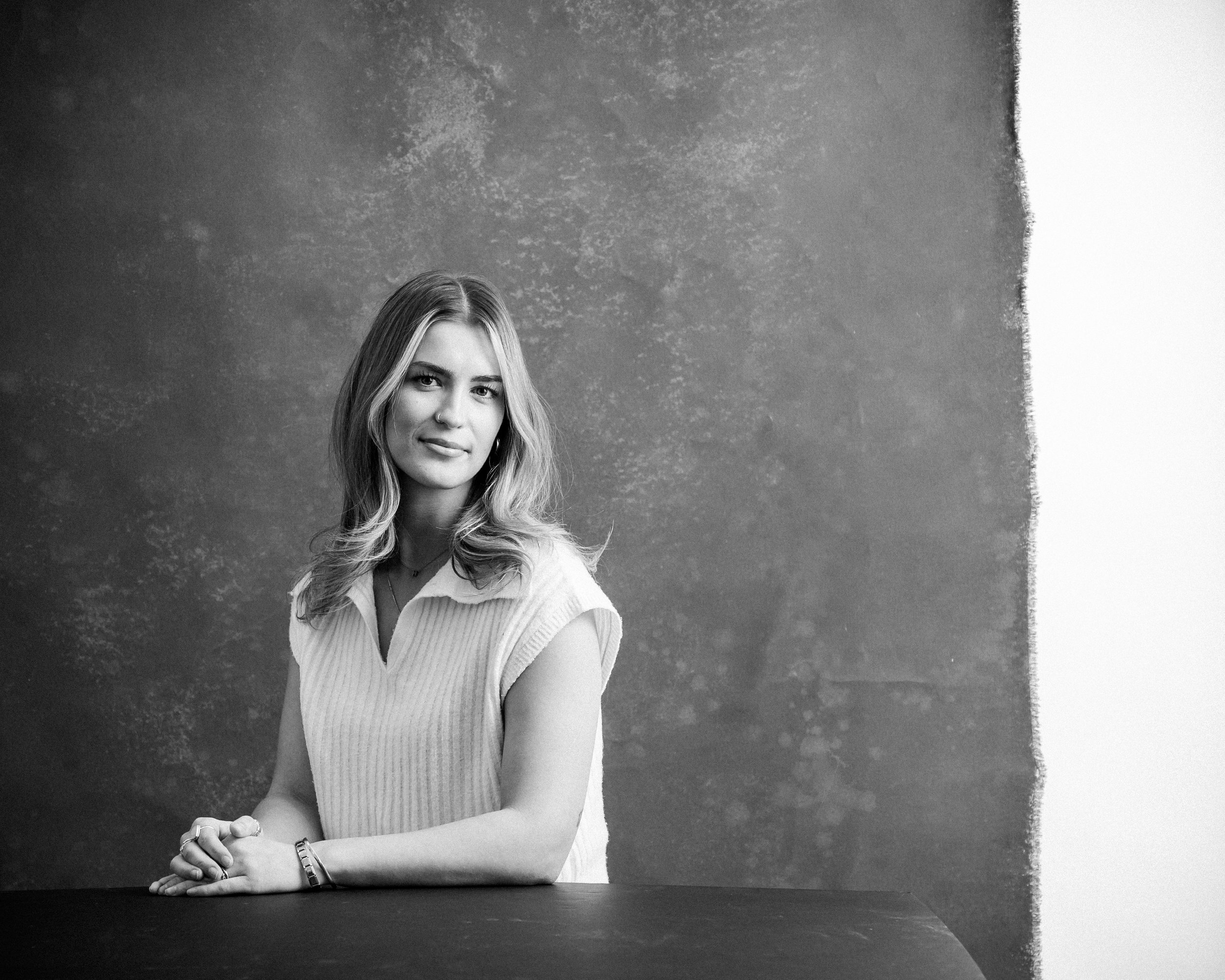 Black and white photo of a girl posing with her hands on a table