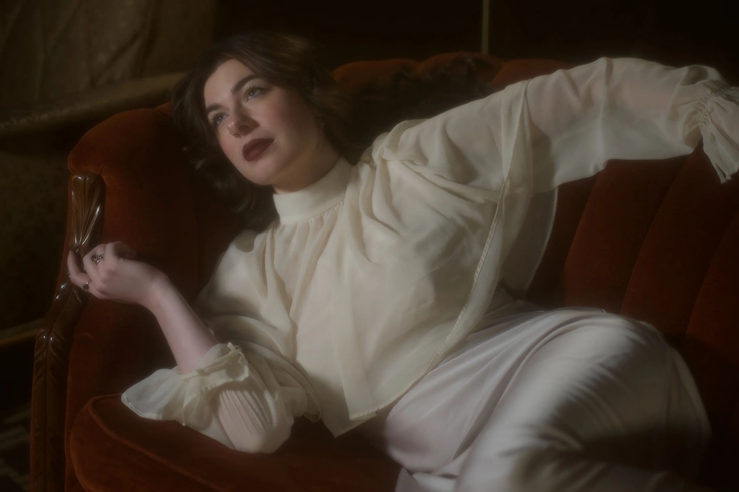 Woman in white dress laying on vintage red couch