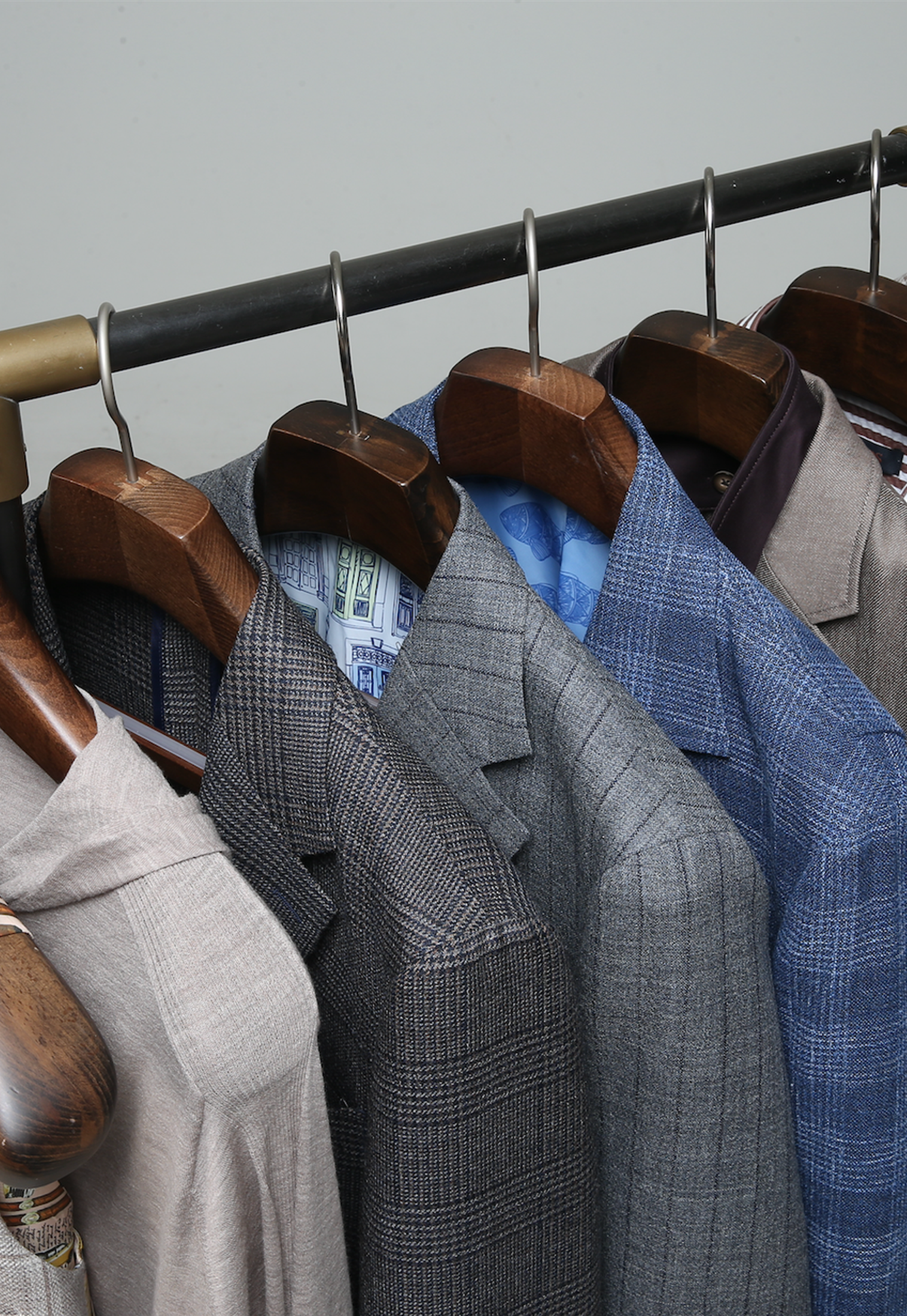 Men's suits hanging on a rack with wooden hangers.