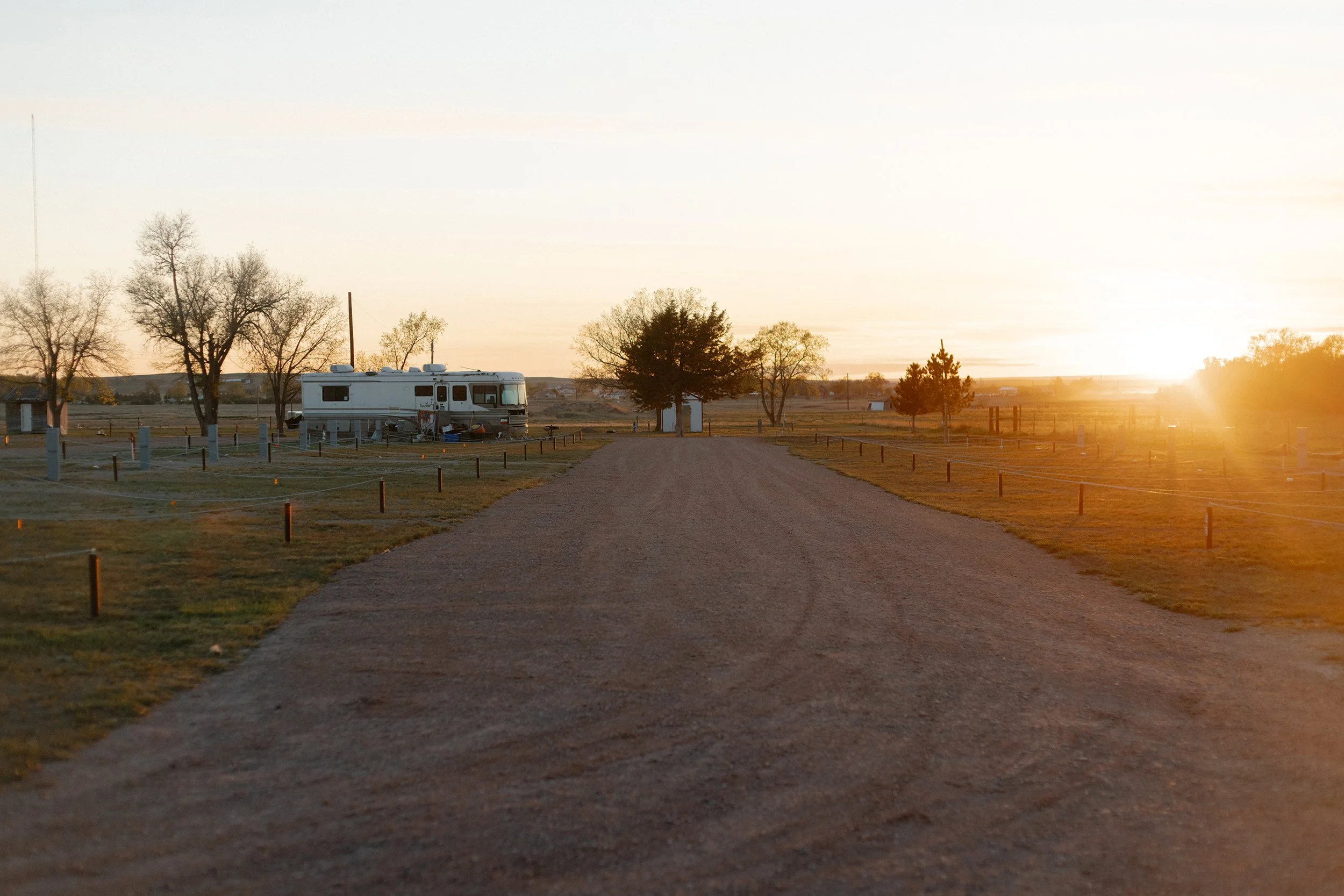 A dirt road leading to a RV park during sunset with trees in Chadron Nebraska