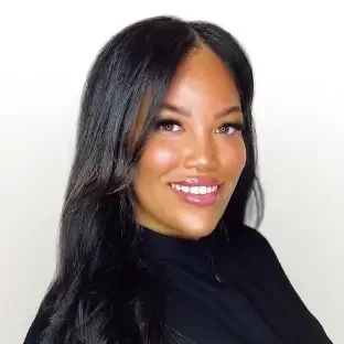 Portrait of a woman with long black hair wearing a black top, smiling against a white background.