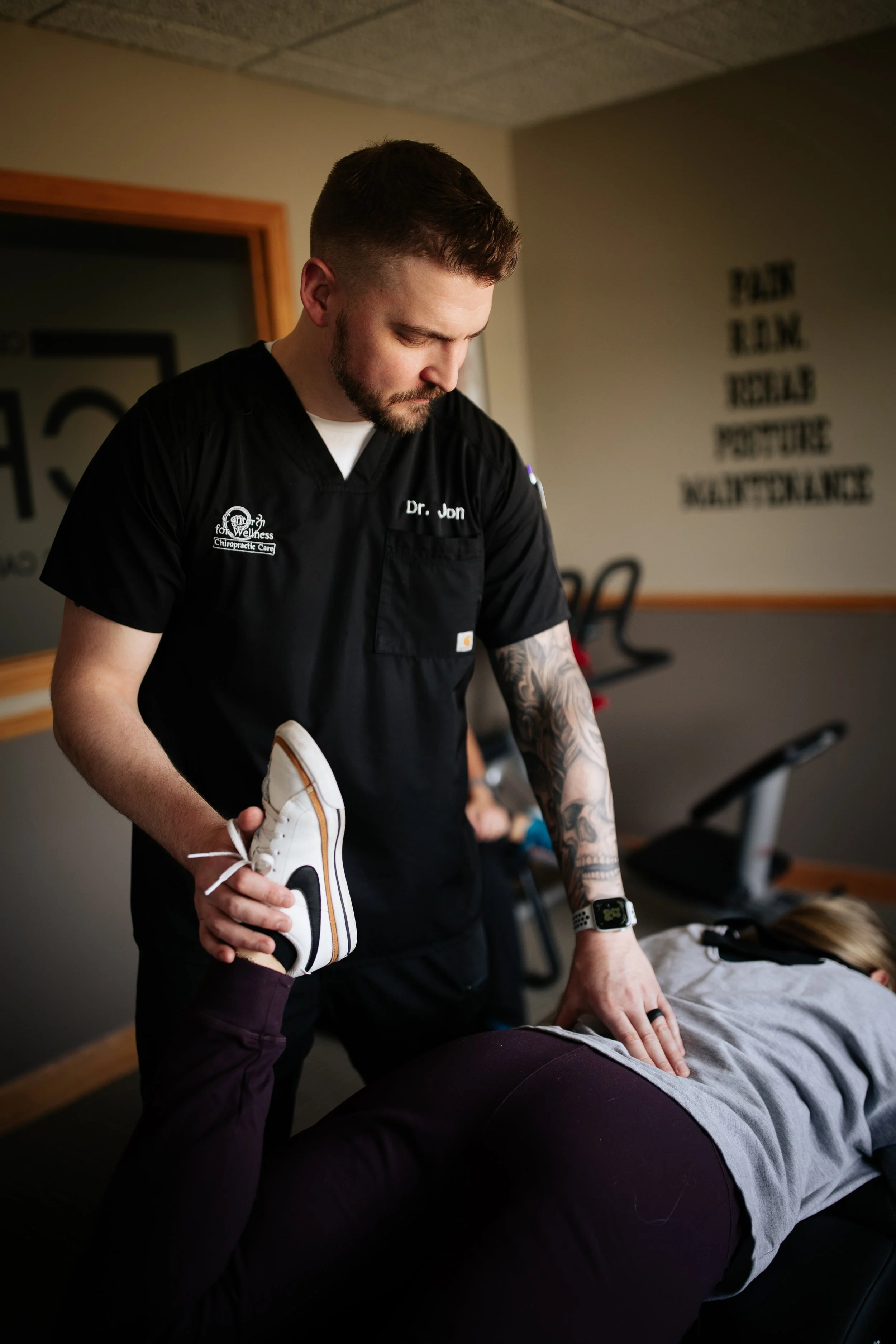Chiropractor performing a spinal adjustment on a patient lying face down on a treatment table in a chiropractic clinic.