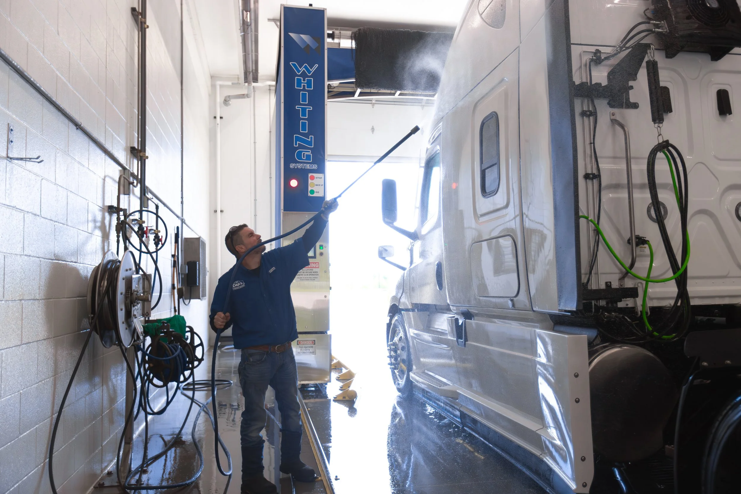 A Cap's Truck Wash Attendant detailing a commercial truck inside truck wash.