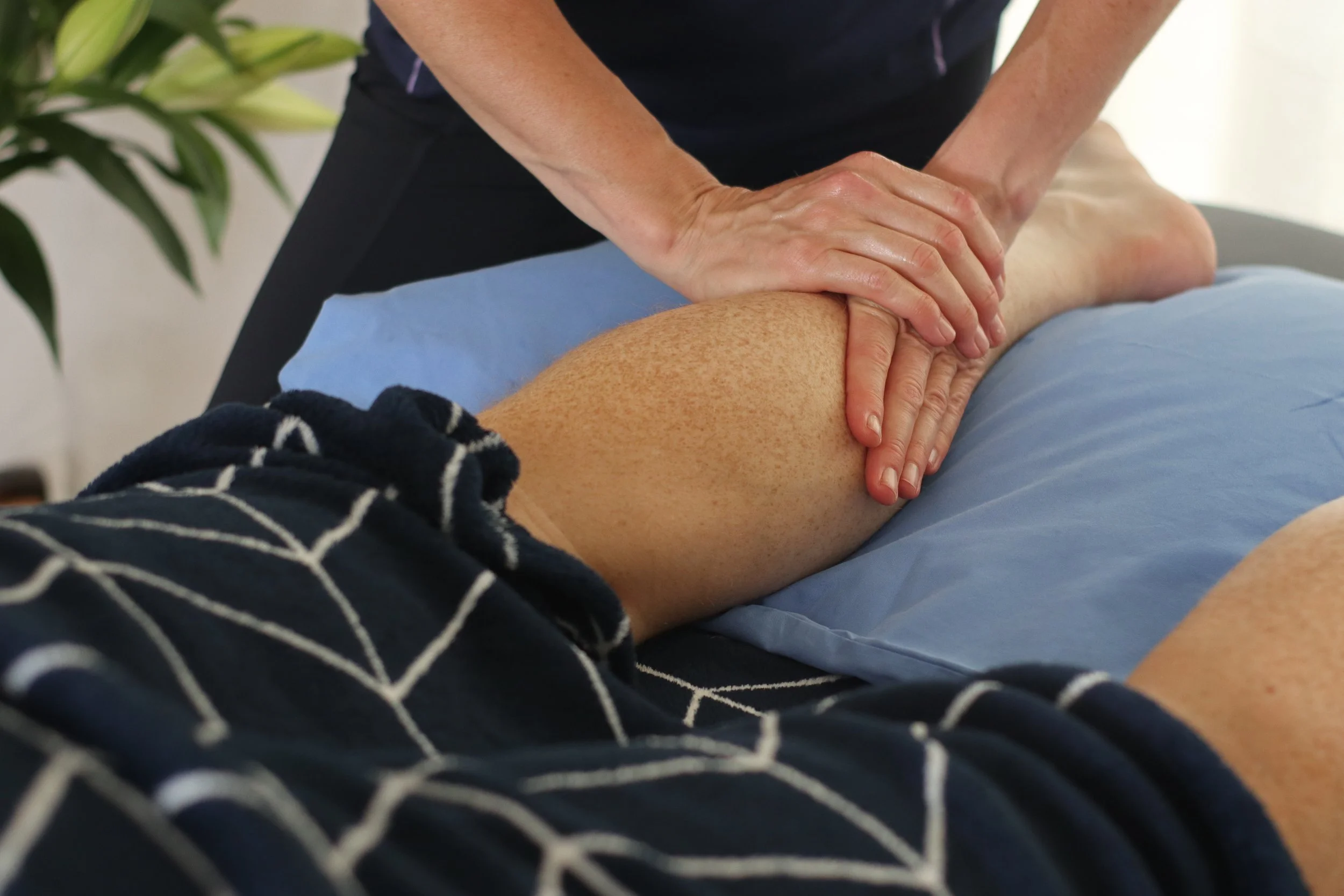 A person receiving a physical therapy or massage on their calf, with the therapist applying pressure with hands.