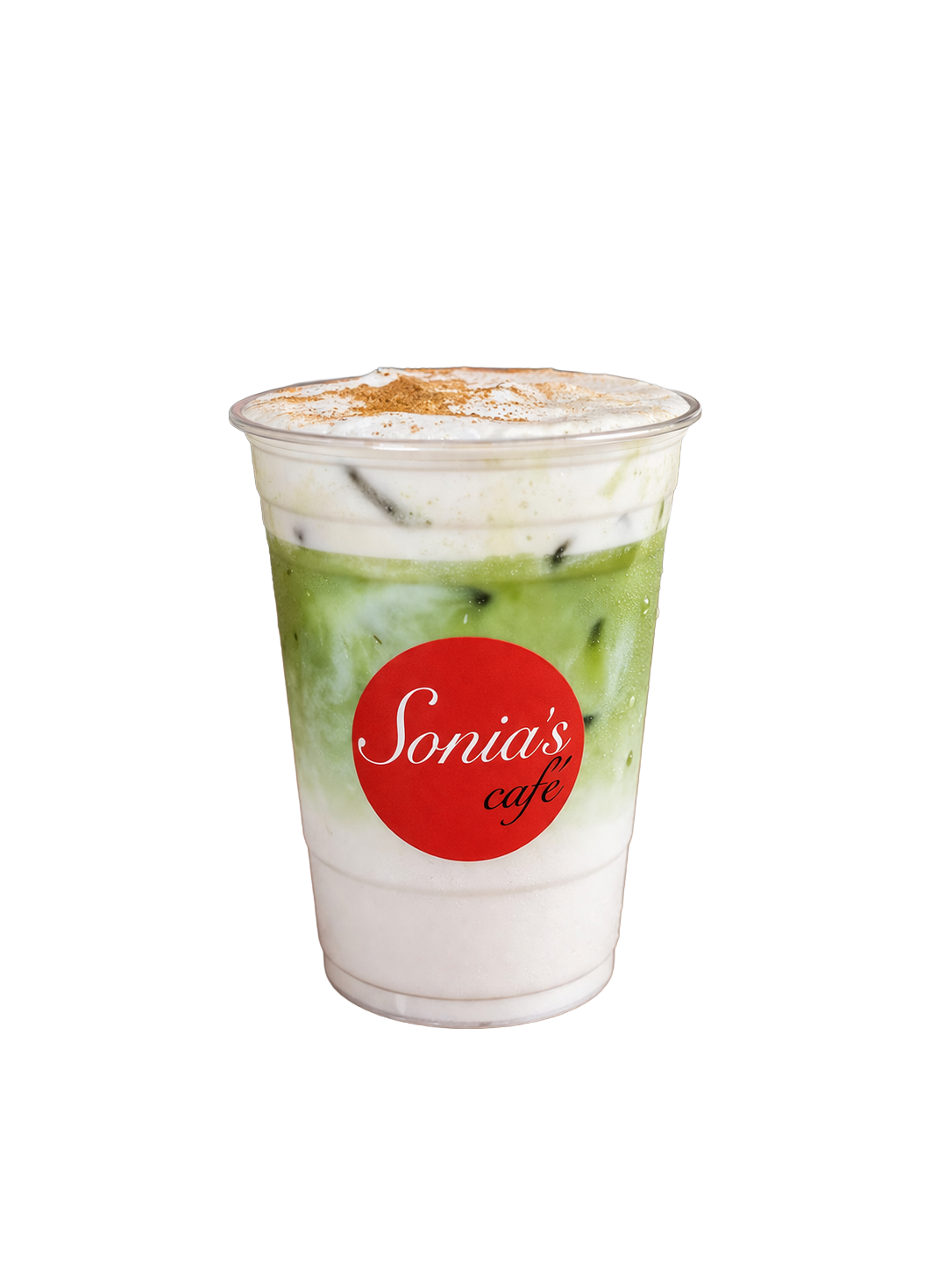 A plastic cup with a red circular label reading 'Sonia's café' contains a layered iced matcha latte topped with whipped cream and sprinkled cinnamon or cocoa powder.