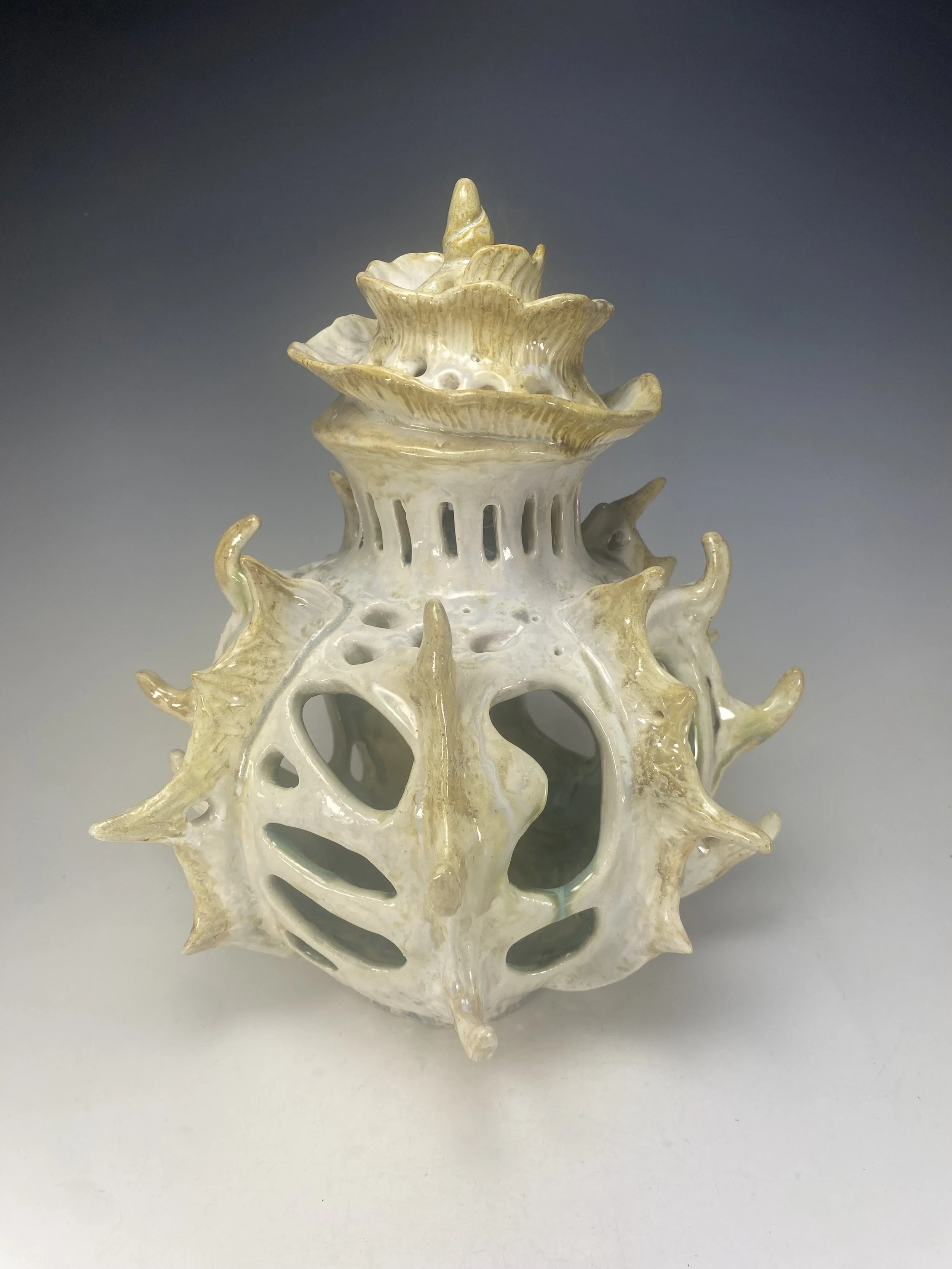 A ceramic sculpture resembling a coral with intricate branching and textured surface, glazed in shades of white and beige.