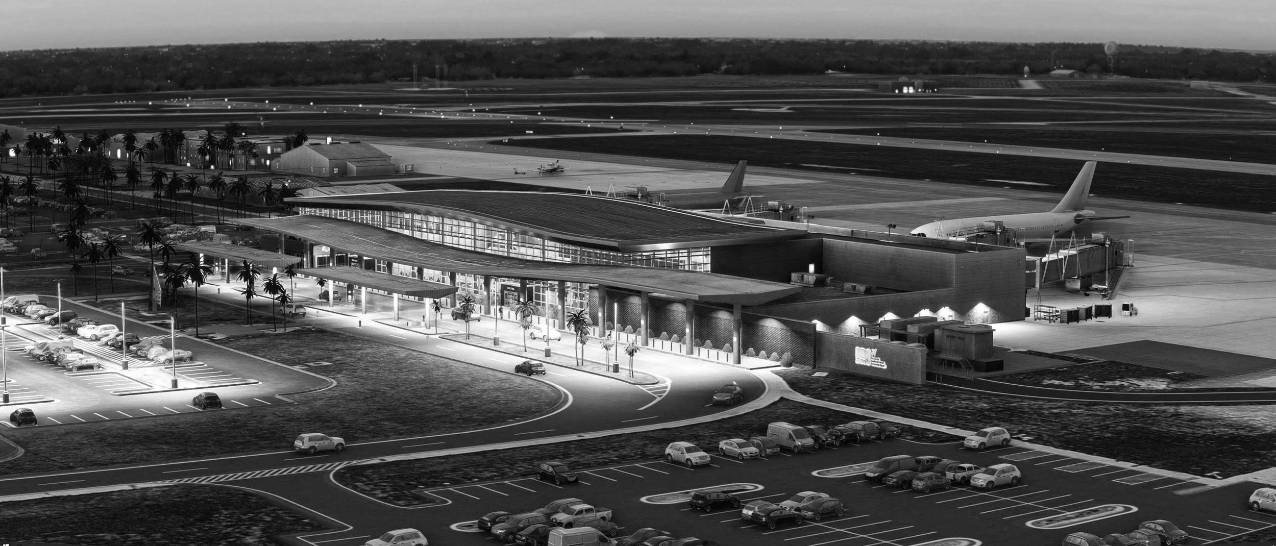 Black and white aerial view of a modern airport terminal with parked cars and planes on the tarmac, surrounded by a runway and airport infrastructure at dusk.