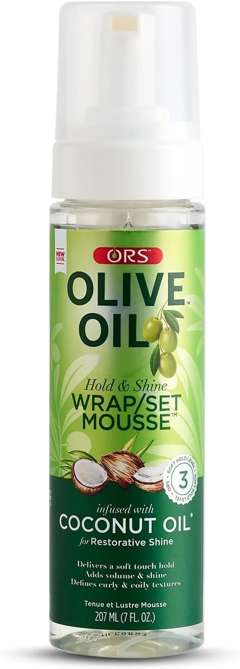 A clear spray bottle of ORS Olive Oil Hold & Shine Wrap/Set Mousse with infused coconut oil, containing 207 milliliters, featuring a green label with images of olives and a coconut, and text highlighting its benefits for hair styling.