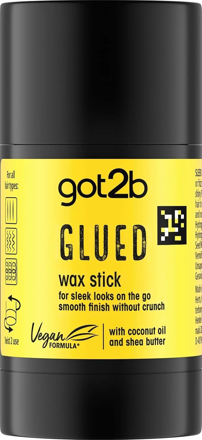 A black container of got2b glued wax stick with a yellow label, indicating it is vegan, contains coconut oil and shea butter, suitable for all hair types, and meant for a sleek, smooth finish on the go.