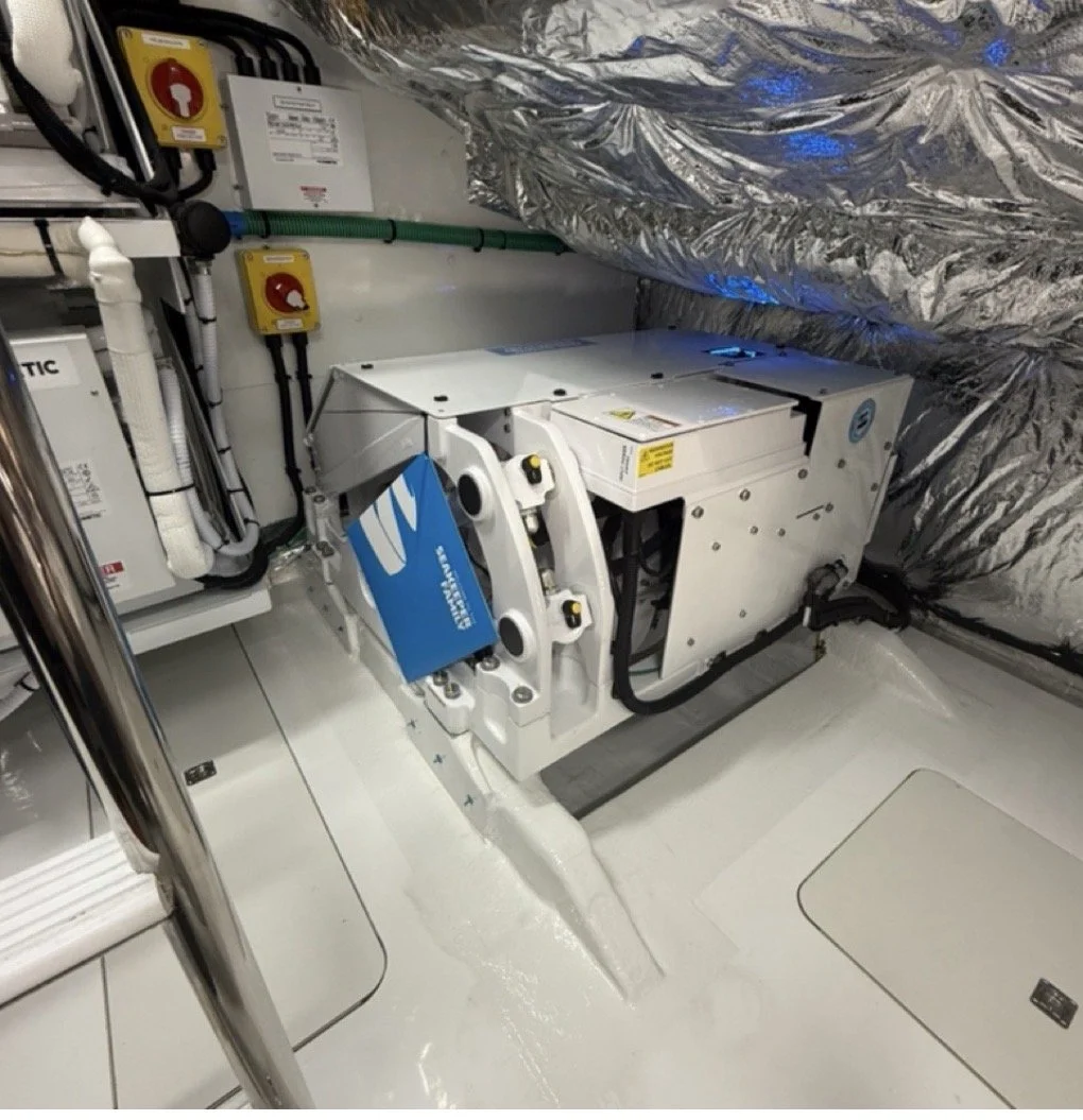 Close-up of a mechanical system with electrical wiring and control panels, installed inside a metallic, insulated enclosure.