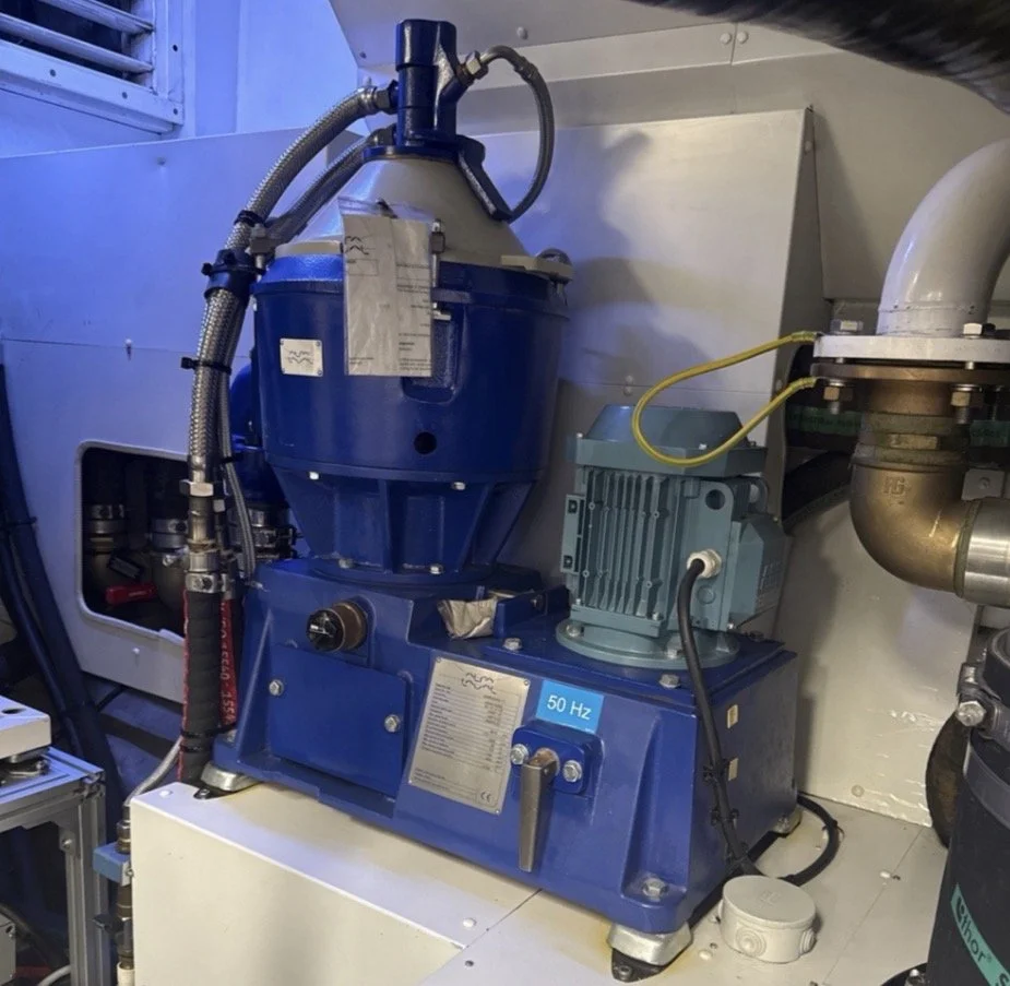 Laboratory or industrial equipment with a blue motor, metallic hoses, and piping, labeled with a blue sticker that says "50 Hz".