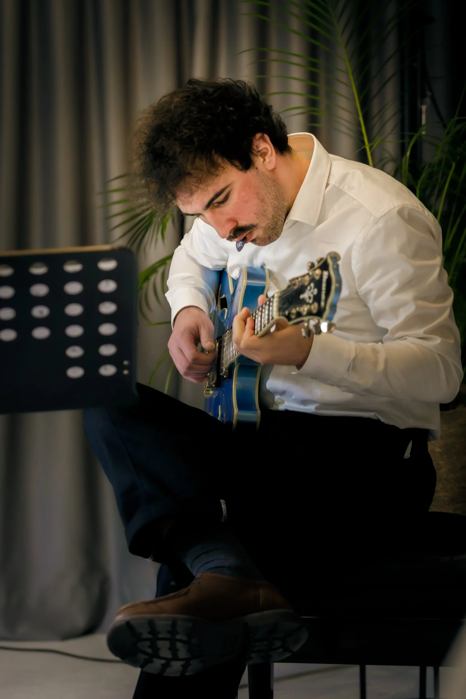 Un homme joue de la guitare électrique dans une pièce avec des plantes et des décorations modernes.