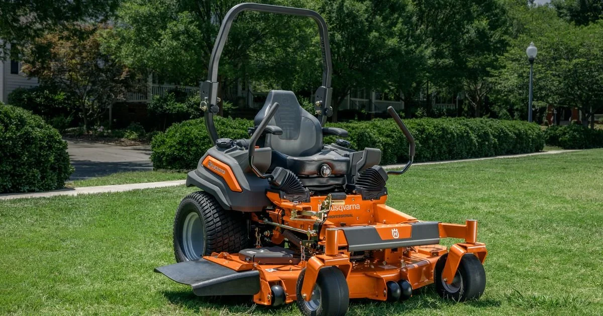 A zero-turn lawn mower on a grassy lawn with trees and shrubs in the background.