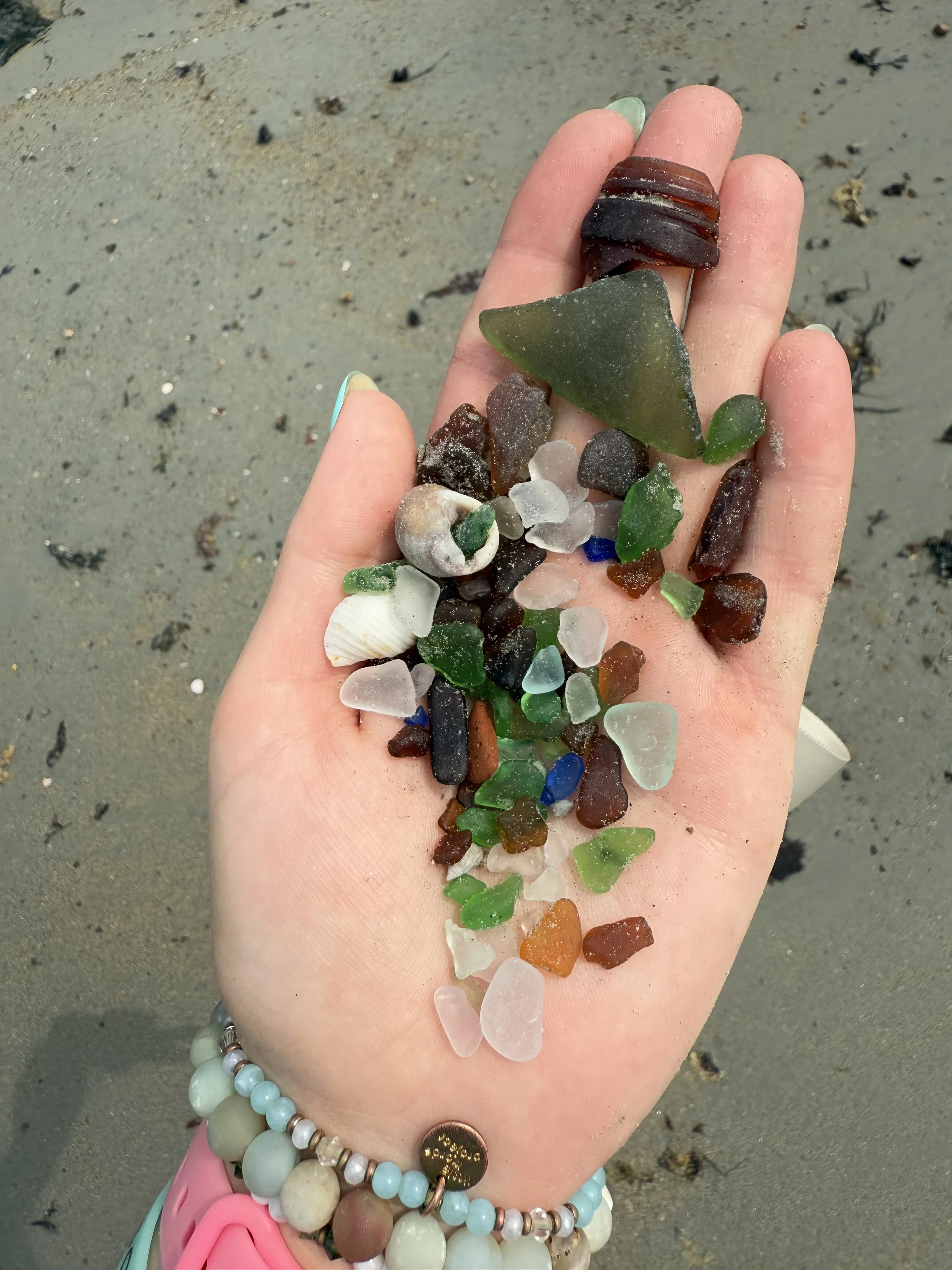 A hand holding an array of seaglass.