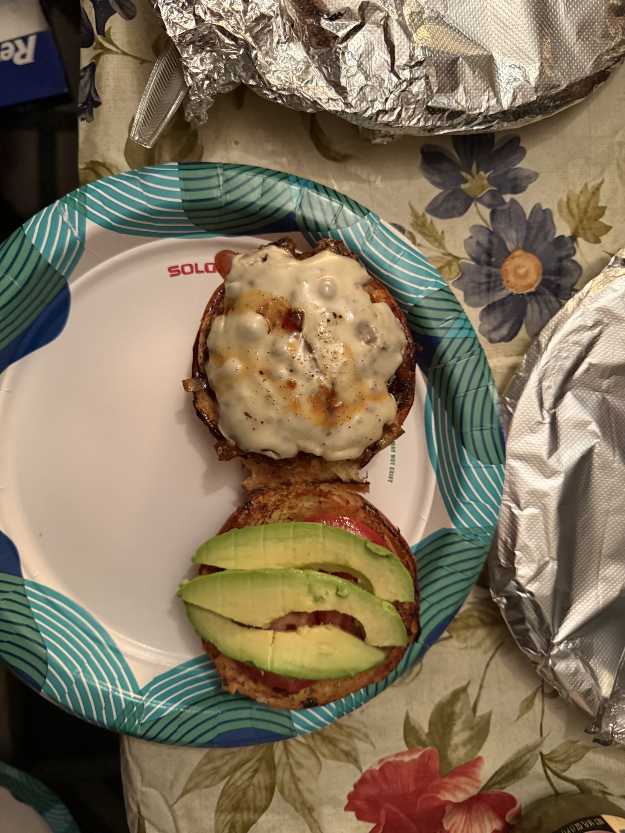 Burger with avocado on a paper plate
