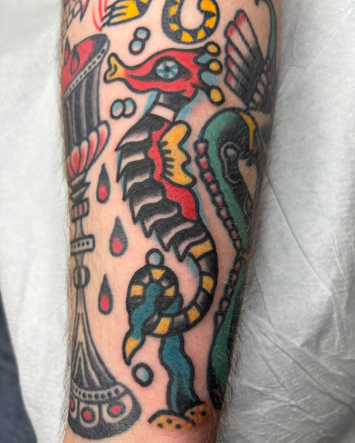 Colorful tattoo of a snake entwined with various abstract shapes and patterns on a person's arm.