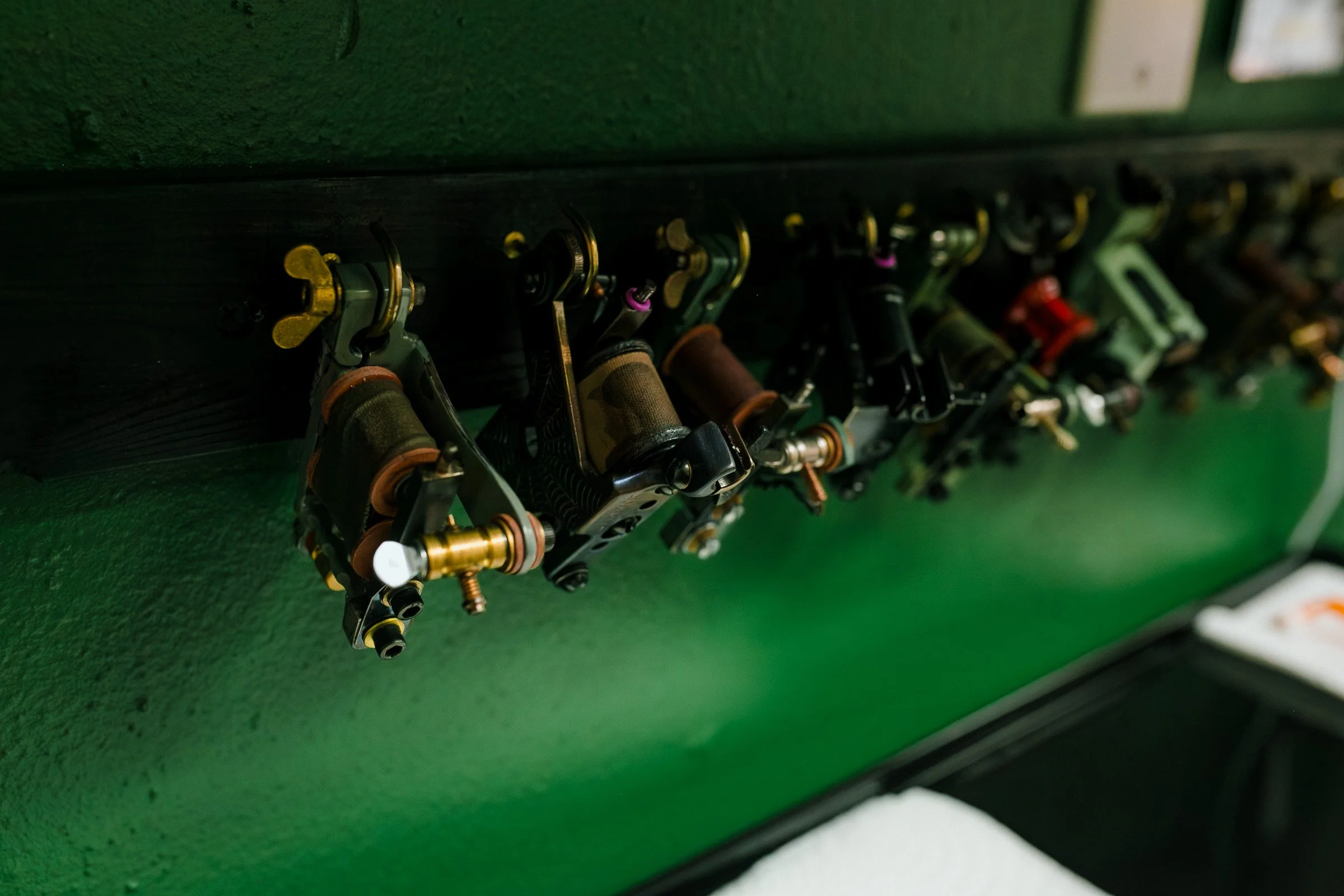 Close-up of a rack of fishing reels mounted on a green surface.
