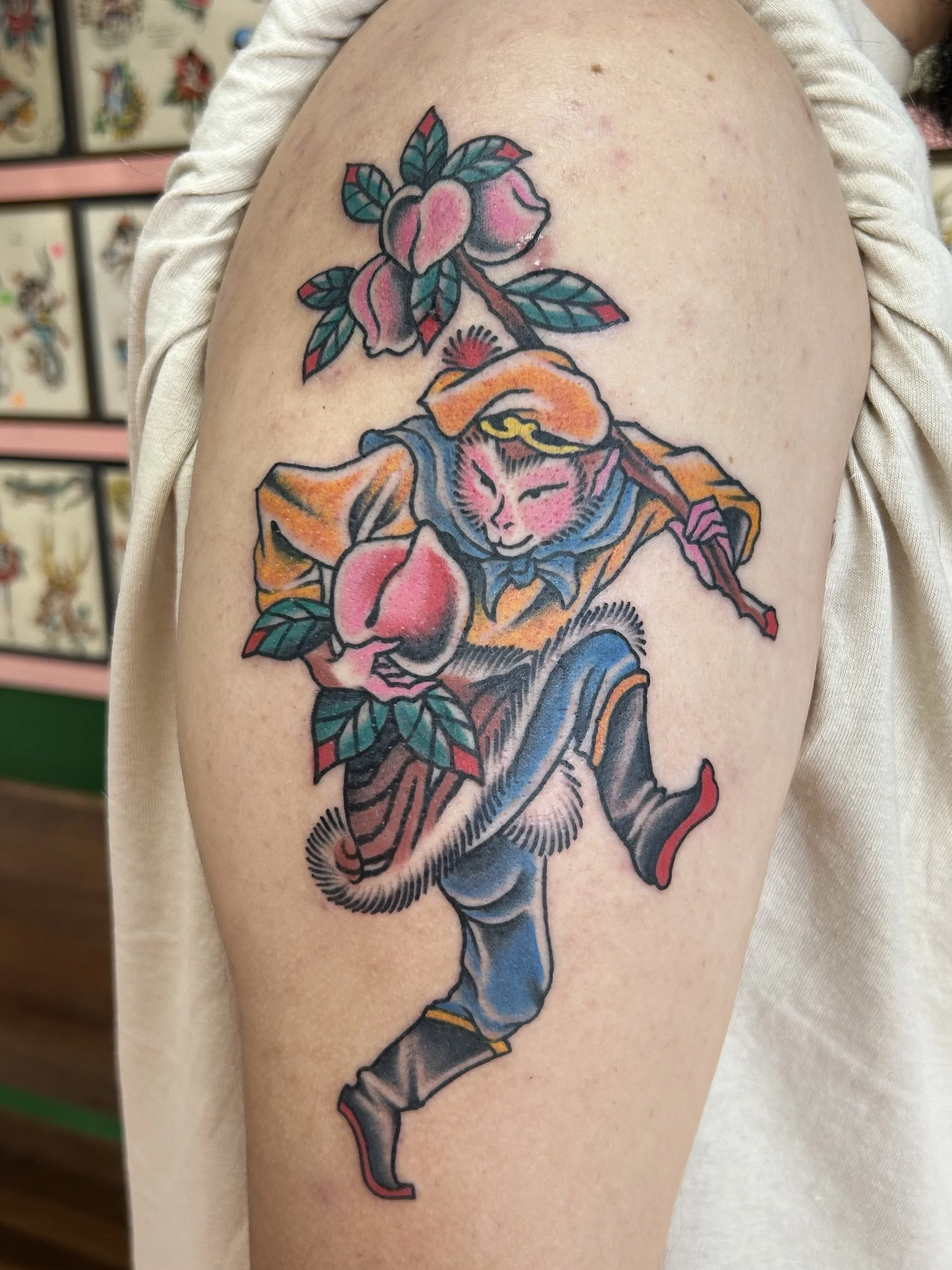 Tattoo of a woman in fancy clothing holding a branch with pink flowers and green leaves.