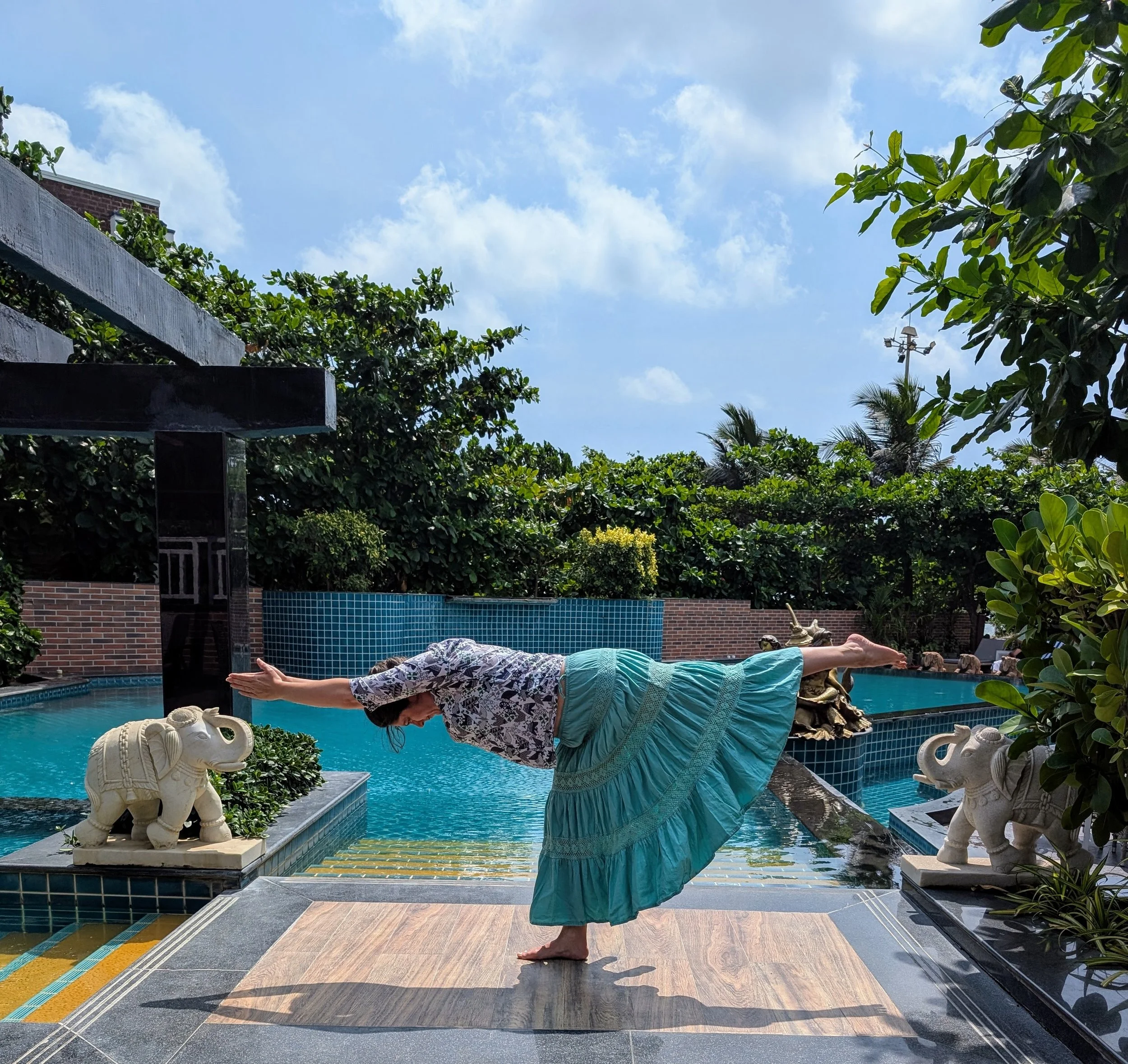 Image of me doing virabadrasana 3 in front of a swimming pool on a sunny day in India.