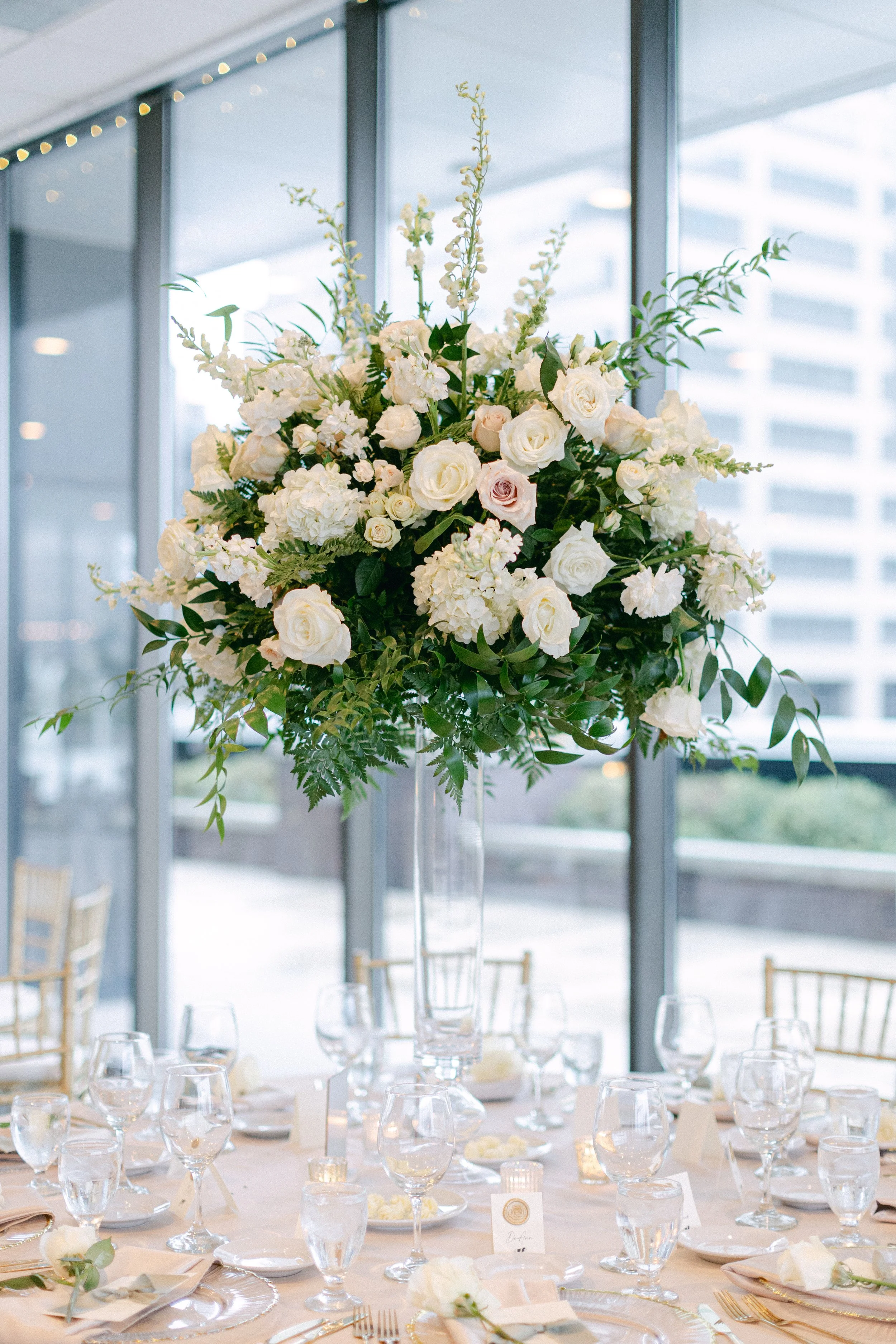 all blush and white rose centerpiece designed by the in-house floral team at JPS Events at Regions Tower, featuring full-service tablescape design, string lights, and floor-to-ceiling window views in downtown Indianapolis.