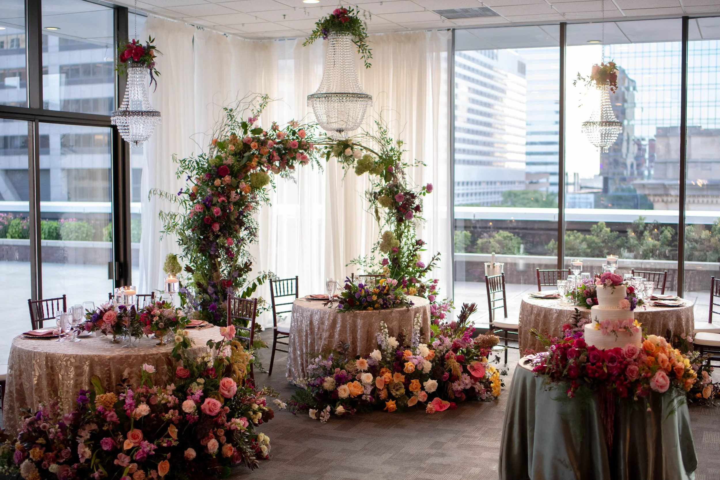 Indoor ballroom wedding reception at JPS Events at Regions Tower, featuring custom pink & purple floral centerpieces created by our in-house design team. Highlights our personalized color-palette design process in downtown Indy.
