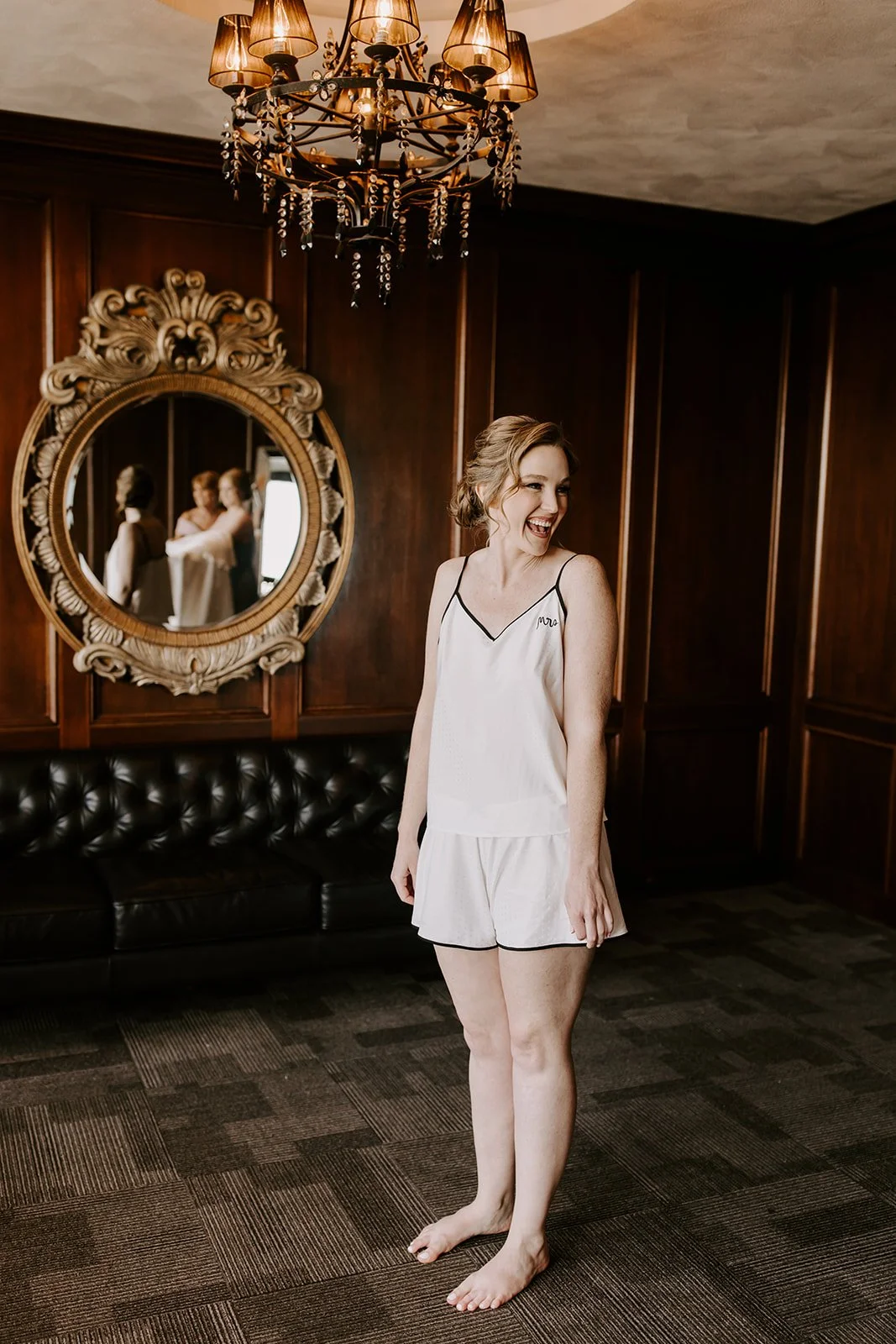Bride getting ready in the private executive suite at JPS Events at Regions Tower, featuring dark wood paneling & crystal chandeliers. Offers dedicated luxury bridal suites & stress-free all-inclusive planning in downtown Indy.