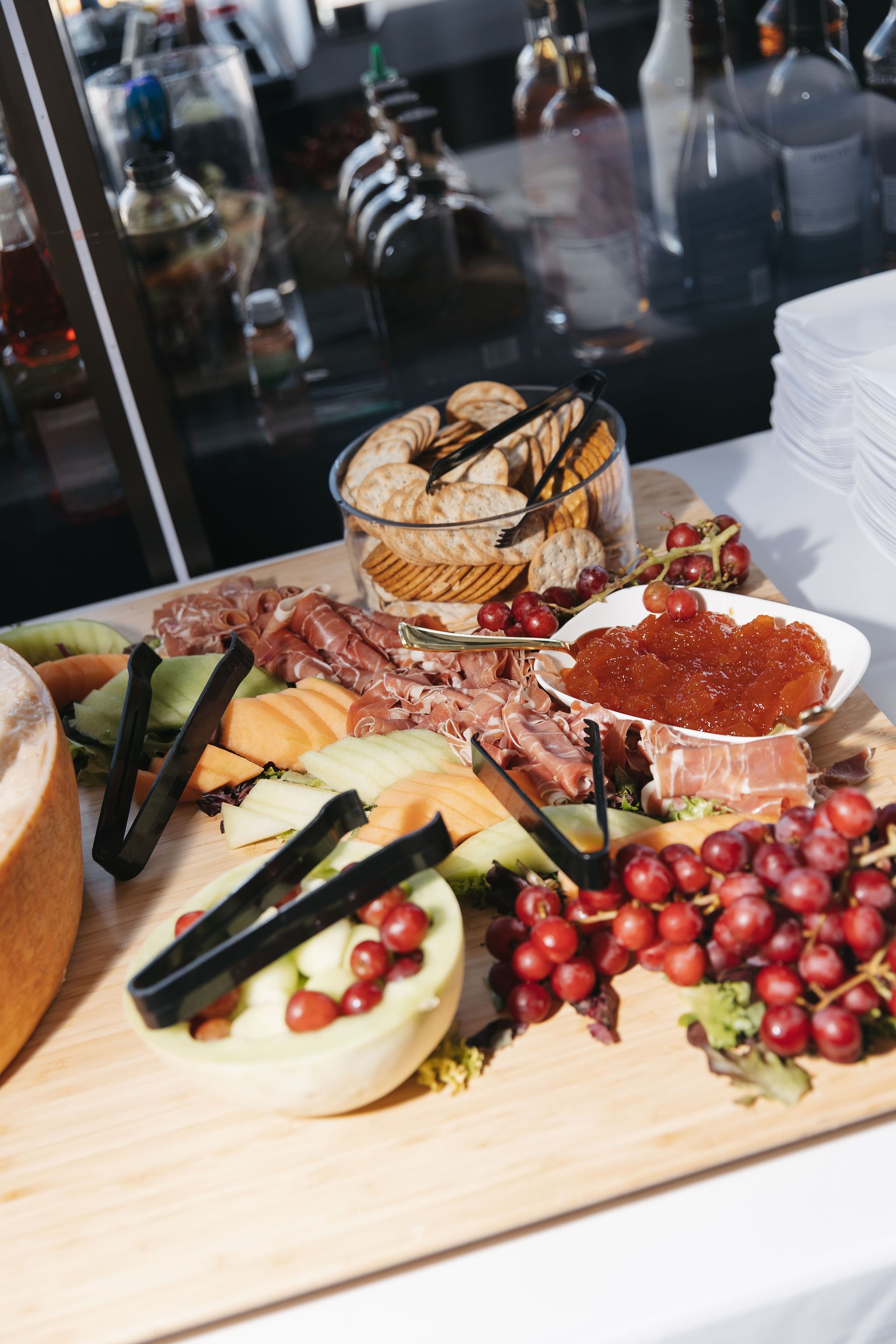 A wooden charcuterie board with cantaloupe, honeydew, watermelon, grapes, jam, and prosciutto from luxury in-house catering at JPS Events at Regions Tower in Downtown Indy. 
