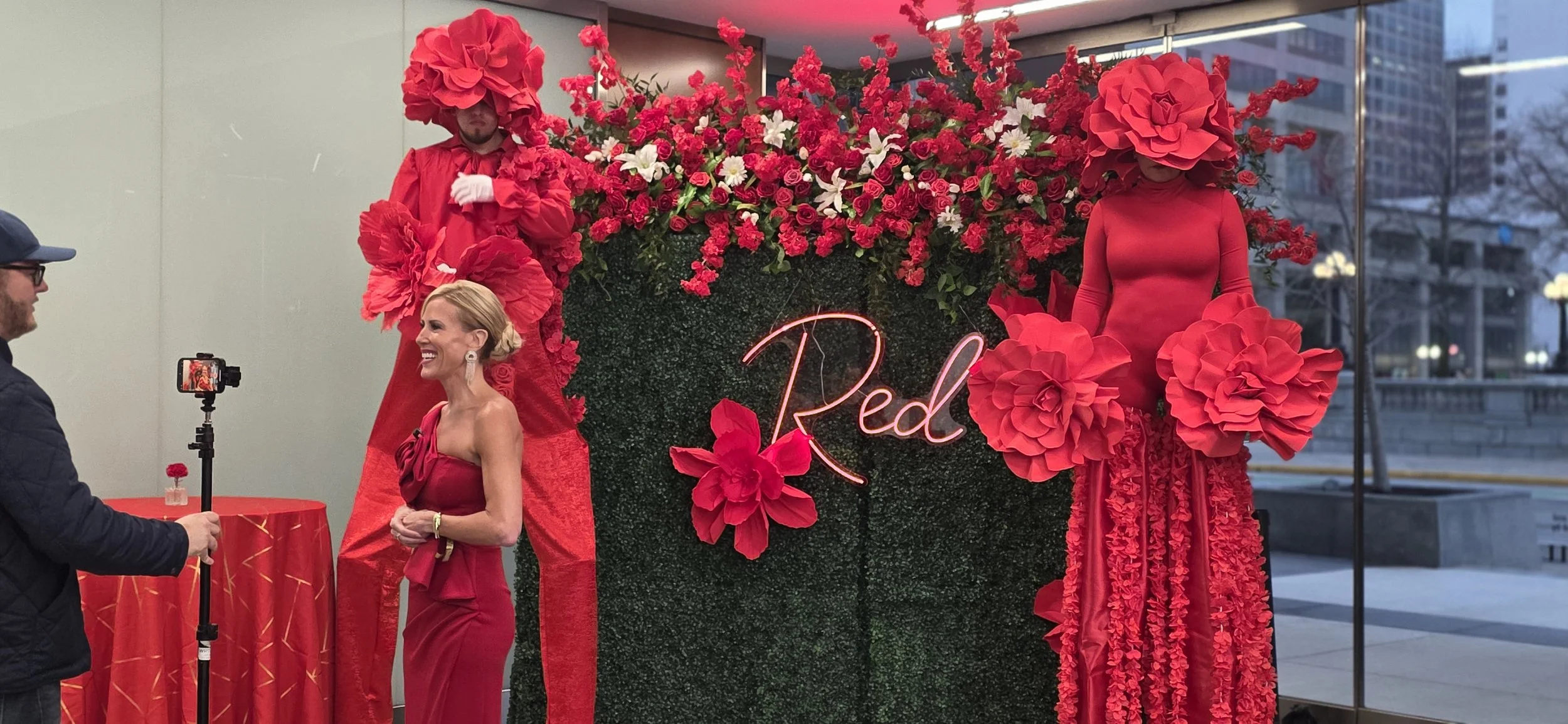 Performers at the Riley RED Gala in front of a custom foliage backdrop with neon branding at JPS Events at Regions Tower, featuring in-house floral design, custom production, an