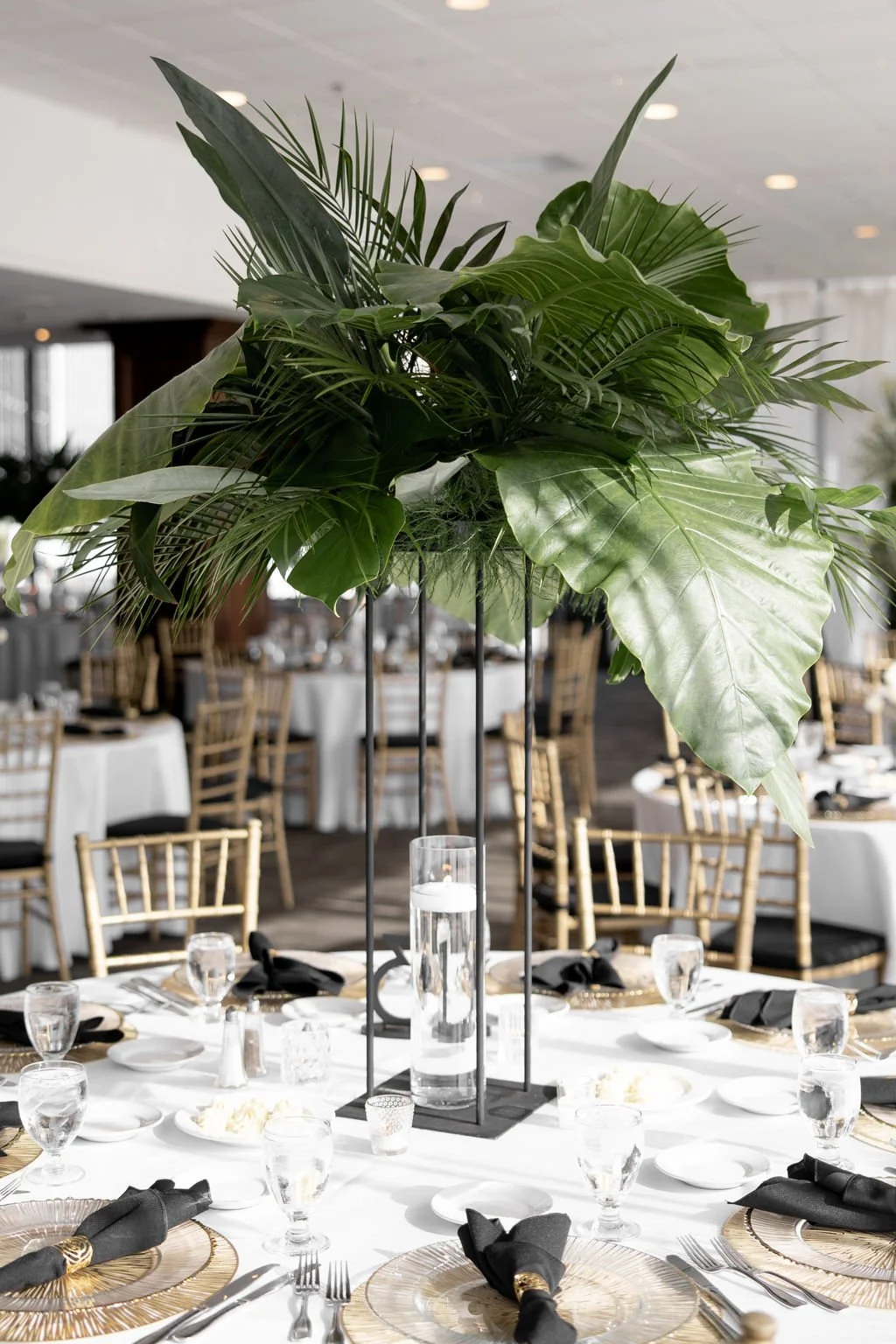 Modern tropical palm leaf centerpiece by the in-house floral team at JPS Events at Regions Tower. Highlights our fully customizable blank-canvas venue with dark wood paneling, brass accents, and wholesale floral pricing in Indy.