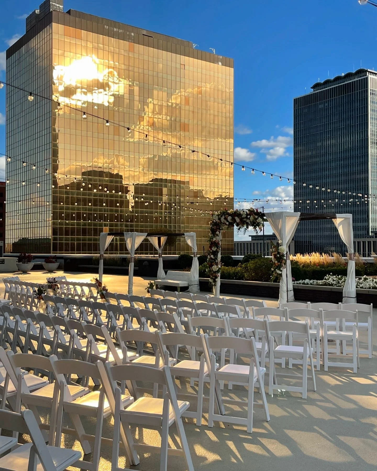 Outdoor rooftop ceremony setup on the 11,000 sq ft 5th-floor terrace at JPS Events at Regions Tower in downtown Indy. Features golden hour skyscraper reflections, 360 skyline views, & all-inclusive coordination.
