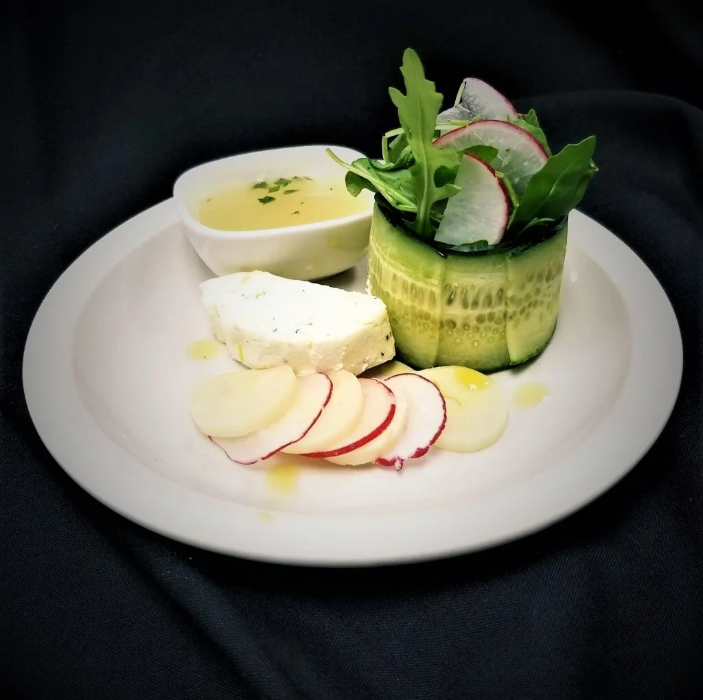 Seasonal selections from luxury in-house catering at JPS Events at Regions Tower: a plate with cucumber salad in a cucumber cup, sliced radishes, cheese, arugula, and dressing at our Downtown Indianapolis wedding venue.