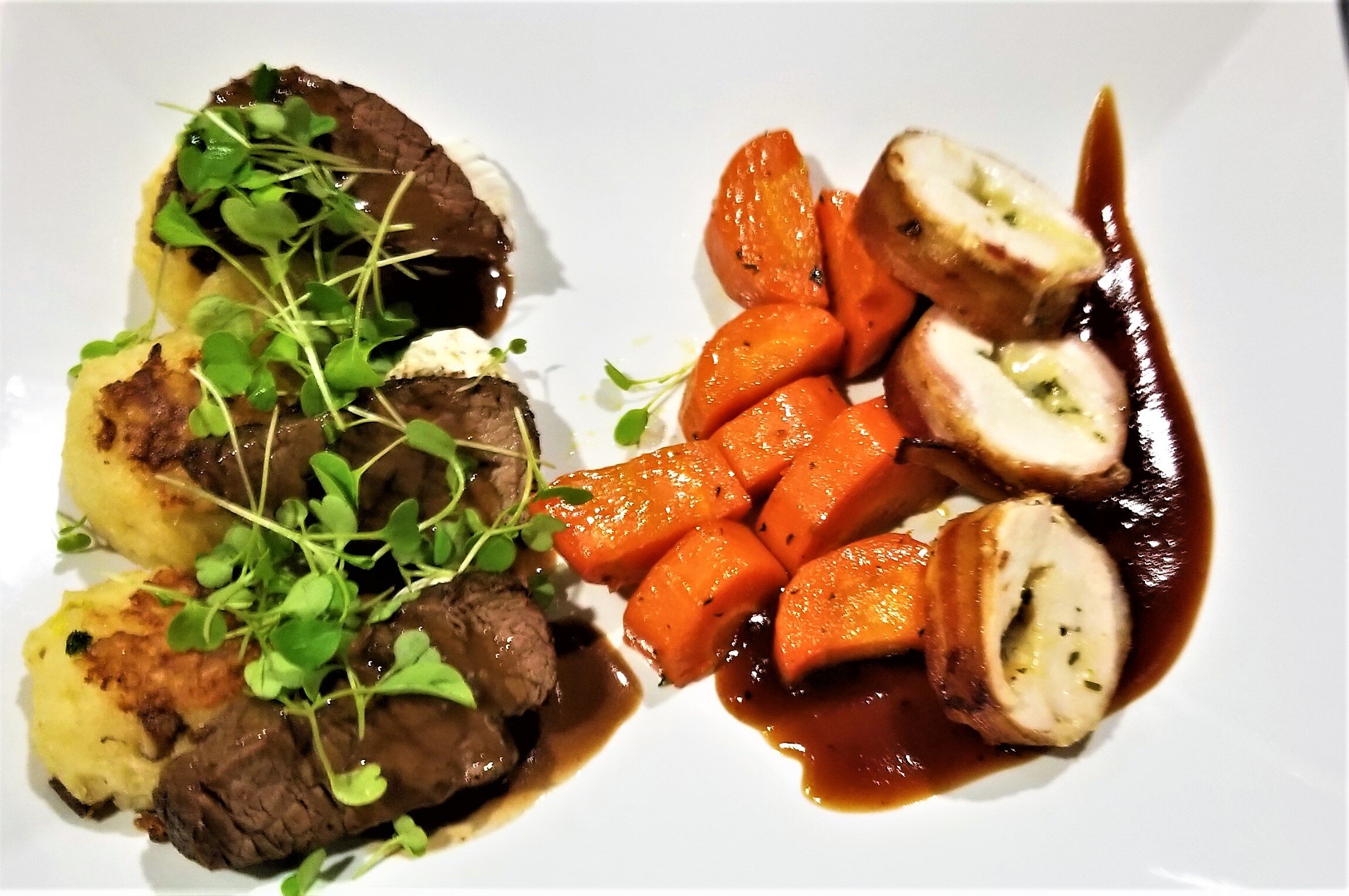 Chef-curated bespoke menus from luxury in-house catering at JPS Events at Regions Tower in Downtown Indy: a plated gourmet meal with cooked meats, beef, carrots, chicken, and microgreens on a white plate.