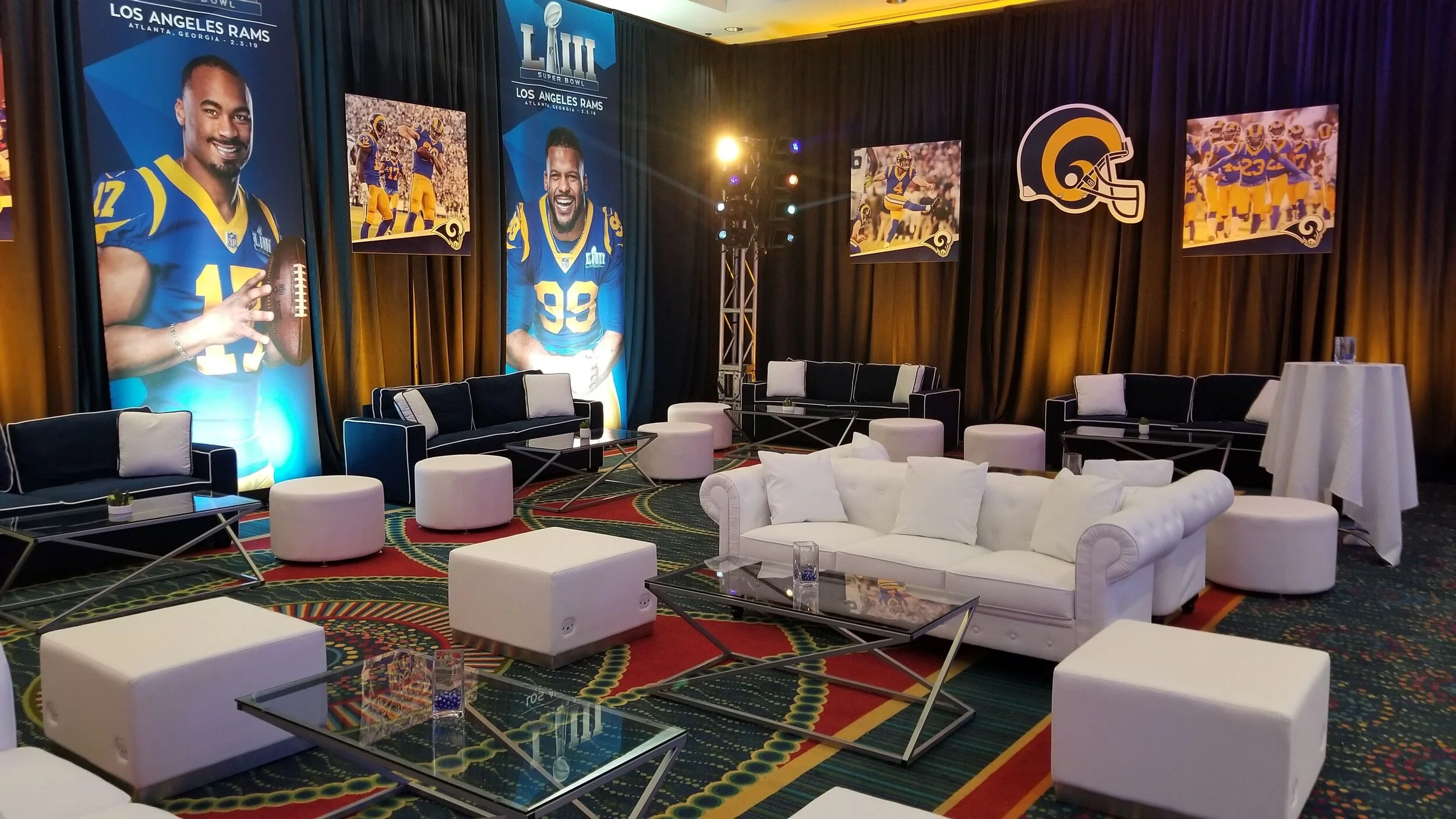 A decorated lounge area with banners and posters of the Los Angeles Rams football team and players, including large images of players in Rams jerseys, and a sign celebrating Super Bowl LIII.