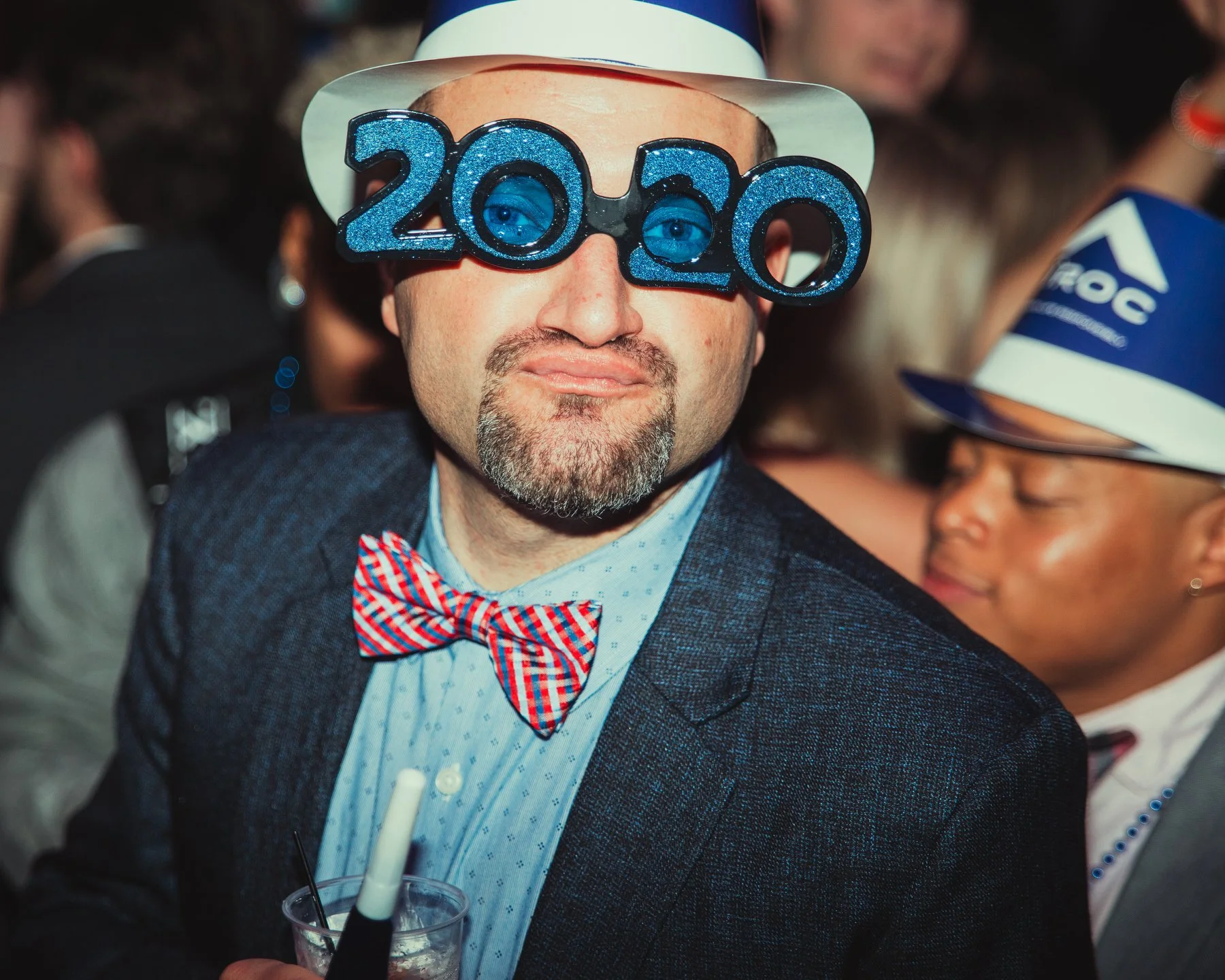 A man wearing white and blue '2020' novelty glasses and a hat at HOT NYE (formerly CÎROC the New Year) at JPS Events at Regions Tower in Downtown Indy, celebrating at the Midwest's premier New Year's Eve party.  