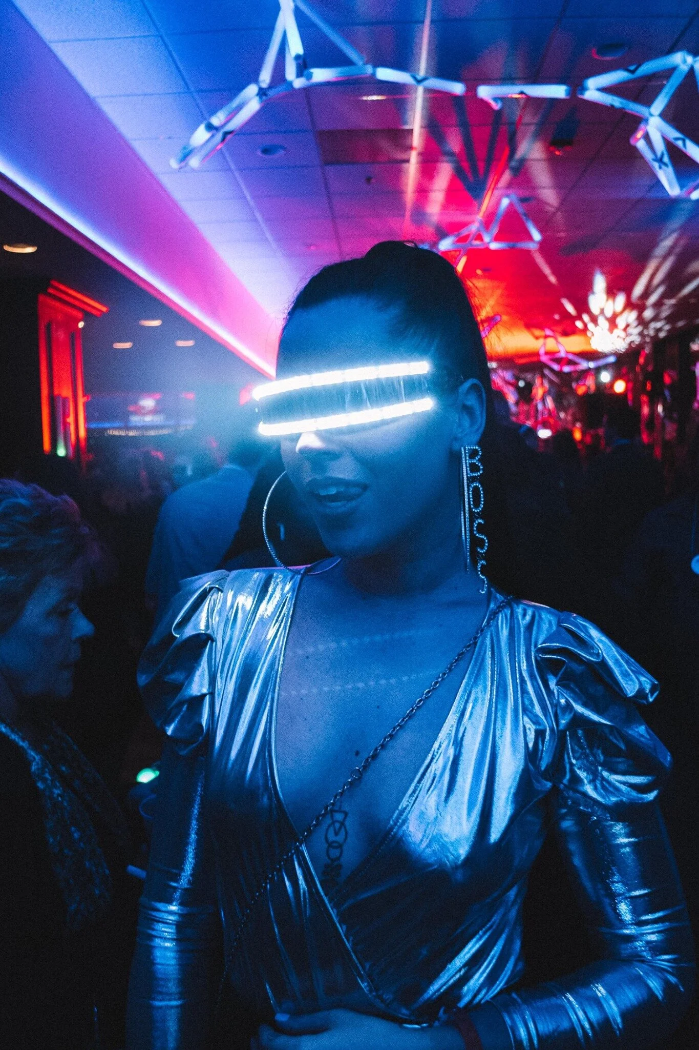 Woman wearing silver metallic outfit and illuminated glasses at a colorful indoor party with neon lights at HOT NYE (formerly CÎROC the New Year) at JPS Events at Regions Tower, the Midwest's premier NYE party in Downtown Indy.  