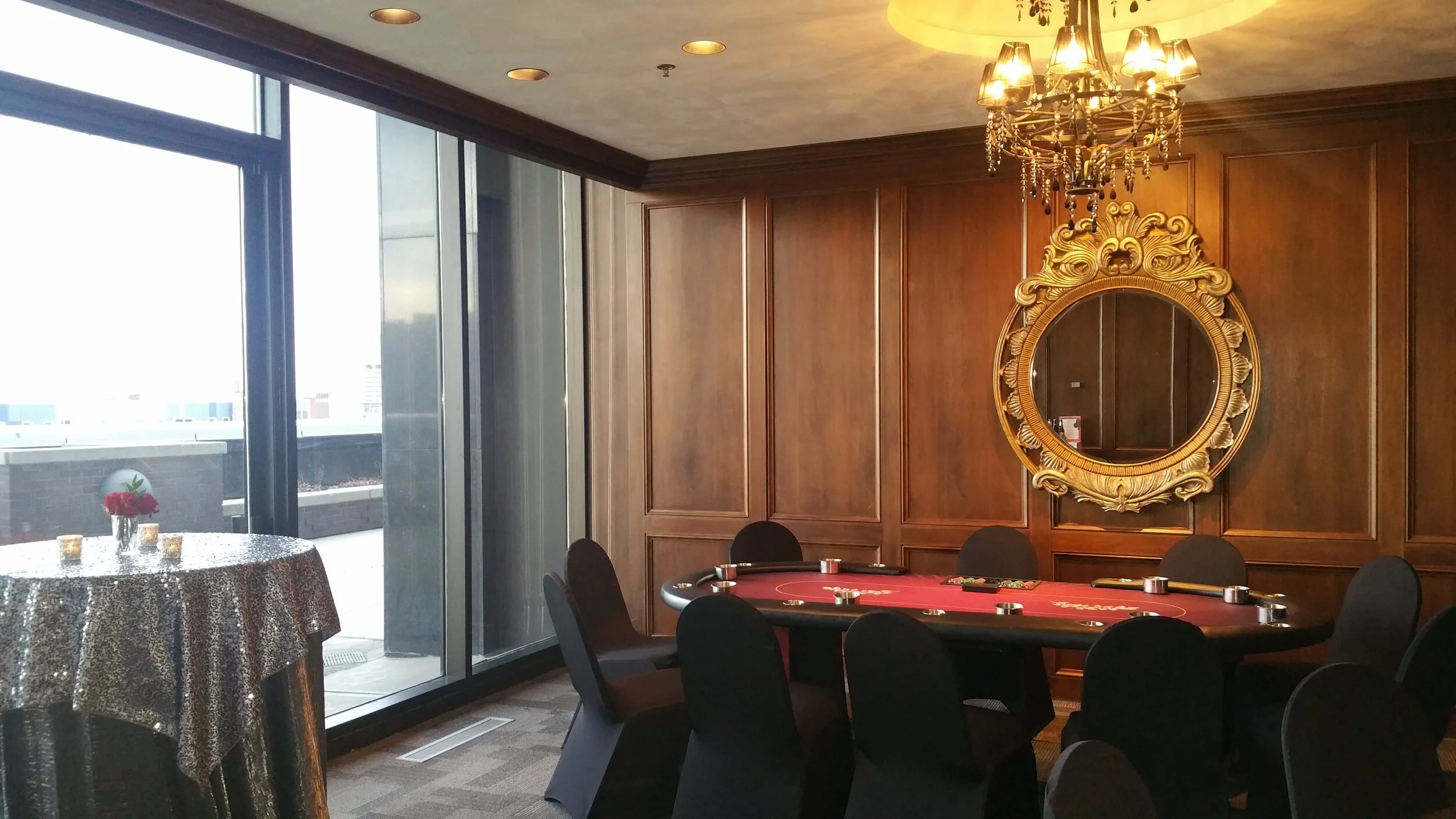 Alt Text: Private corporate casino night in the executive suite at JPS Events at Regions Tower, featuring dark wood paneling, warm architectural chandelier lighting, and all-inclusive event planning services in downtown Indianapolis