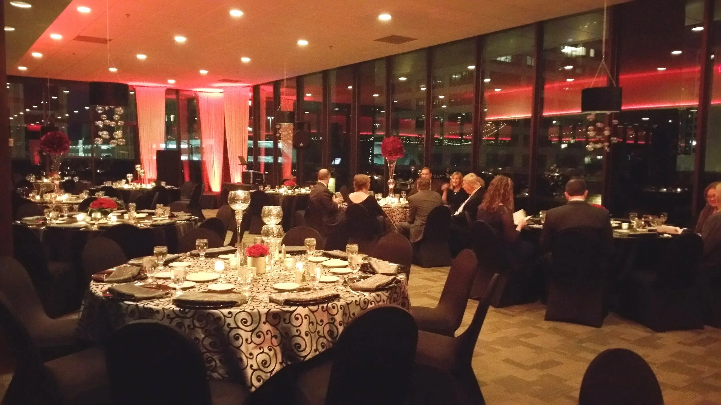 Evening corporate banquet inside the modern indoor ballroom at JPS Events at Regions Tower, featuring polished white marble flooring, in-house luxury floral centerpieces, atmospheric lighting, and all-inclusive event planning.