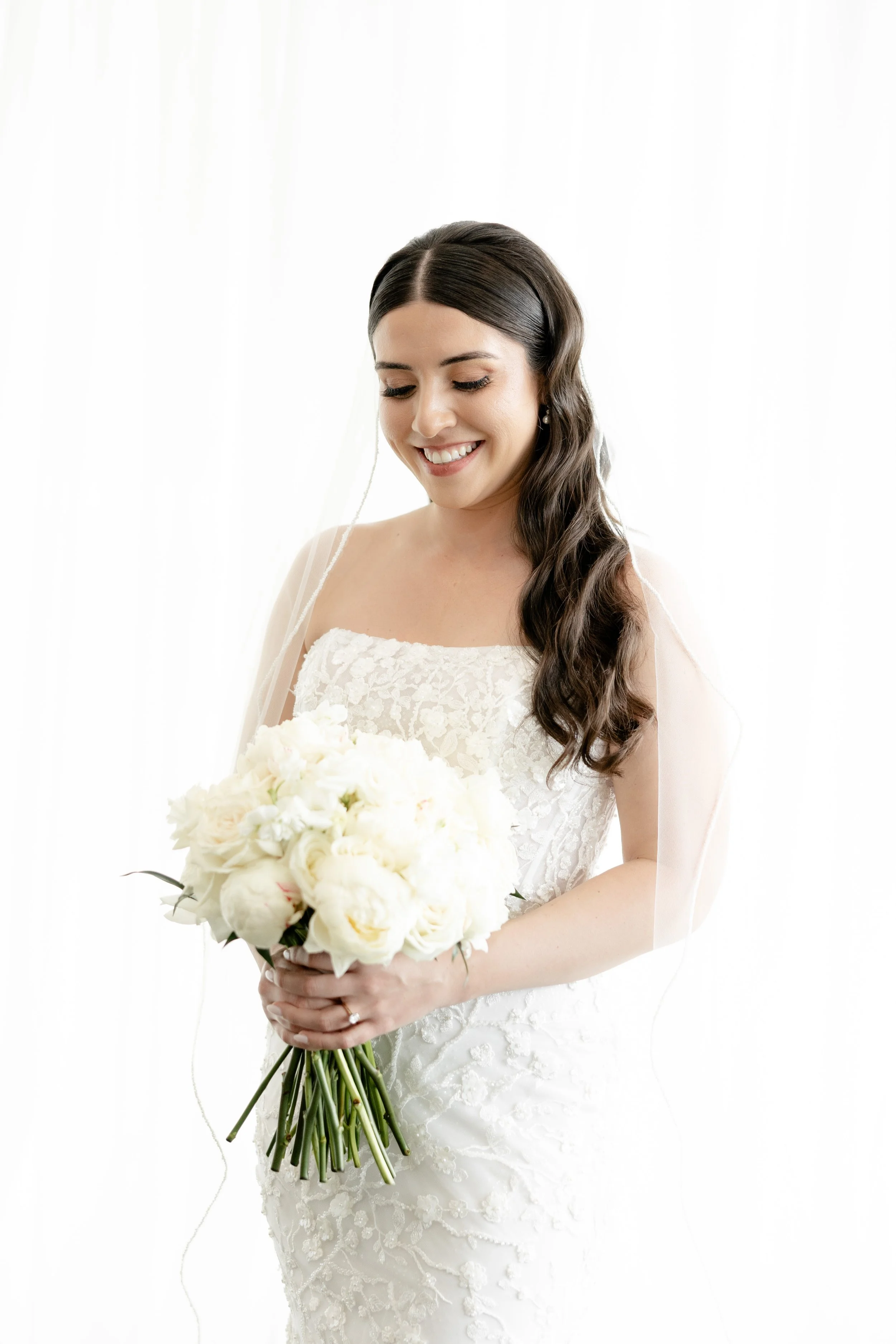 Bride with a lush white rose and peony bouquet designed by the in-house florists at JPS Events at Regions Tower. Features complete setup and teardown, chef-driven catering, and zero late-out fees in downtown Indianapolis.