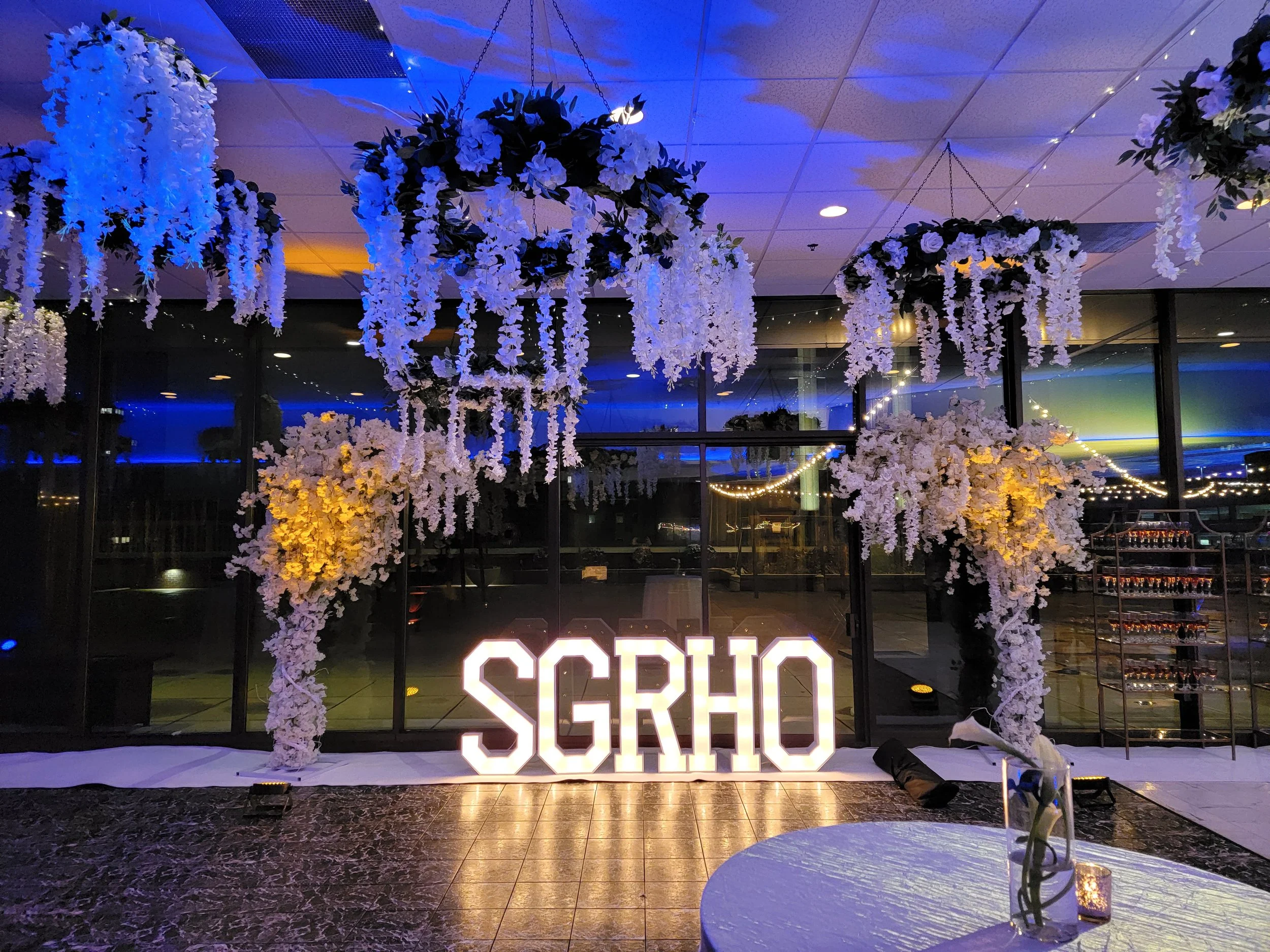 Custom corporate event photo backdrop designed by JPS Events at Regions Tower, featuring in-house luxury floral design, custom illuminated neon branding, and modern architectural lighting in downtown Indianapolis.