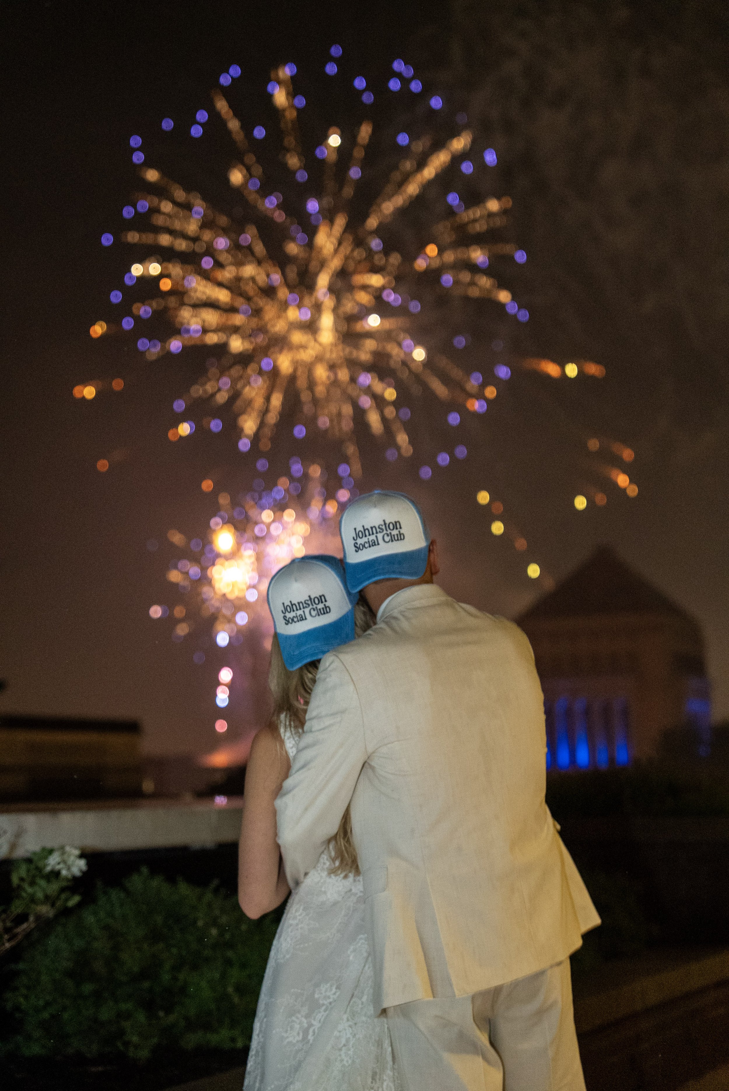 Couple celebrating on the 11,000 sq. ft. 5th-floor penthouse terrace at JPS Events at Regions Tower during a nighttime rooftop wedding reception with 4th of July fireworks over the 360-degree downtown Indianapolis skyline.
