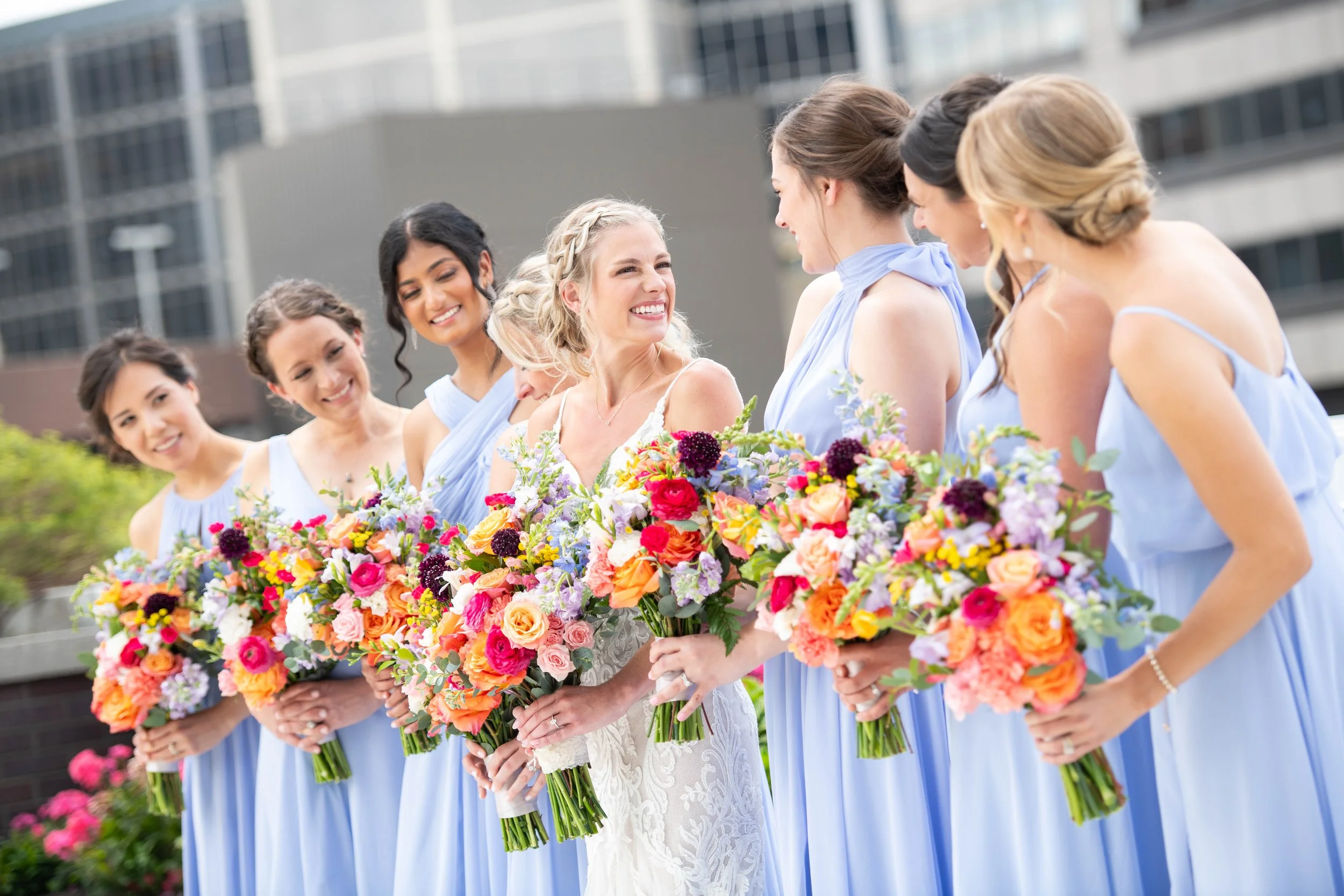 Bride & 6 bridesmaids with vibrant custom bouquets by the in-house floral team at JPS Events at Regions Tower. Features over-the-top wedding florals at wholesale pricing & 360 penthouse terrace views in downtown Indy.
