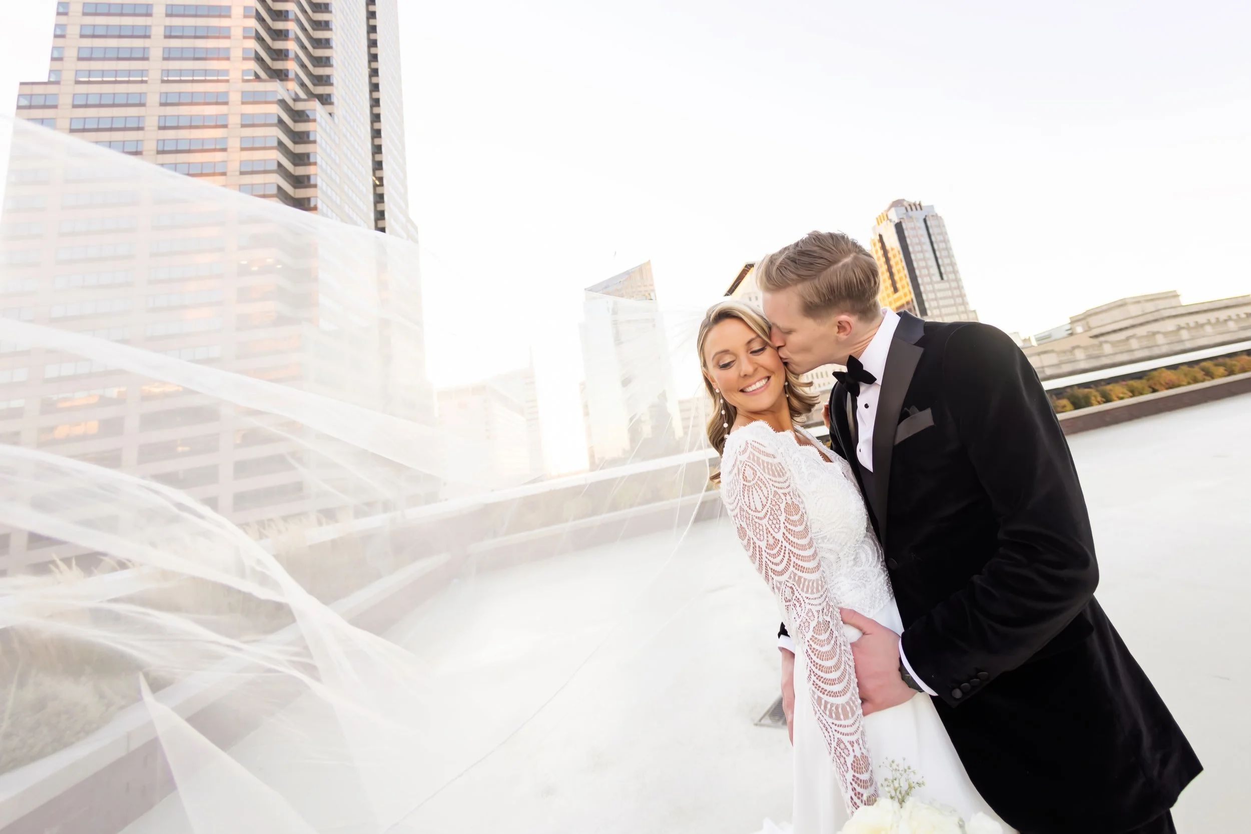 Bride & groom kiss on the 11,000 sq ft penthouse terrace at JPS Events at Regions Tower in downtown Indy. Highlights 360 skyline photo ops, metropolitan chic outdoor space, & full-service day-of coordination.