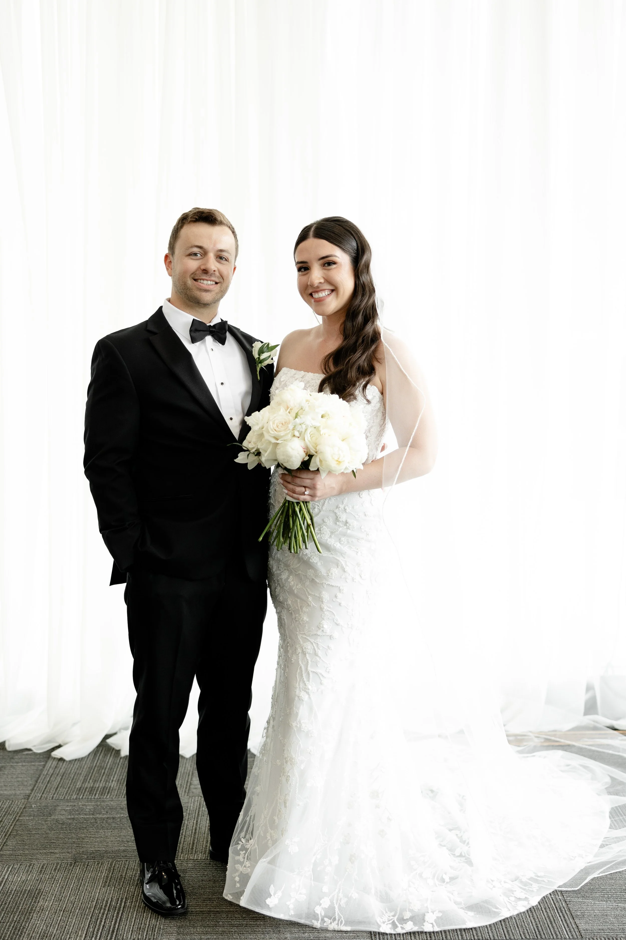 Newlywed portrait at JPS Events at Regions Tower featuring a white rose bouquet by our in-house florists. Offers all-inclusive stress-free planning, chef-driven catering, & 6 walkable hotels in downtown Indy.
