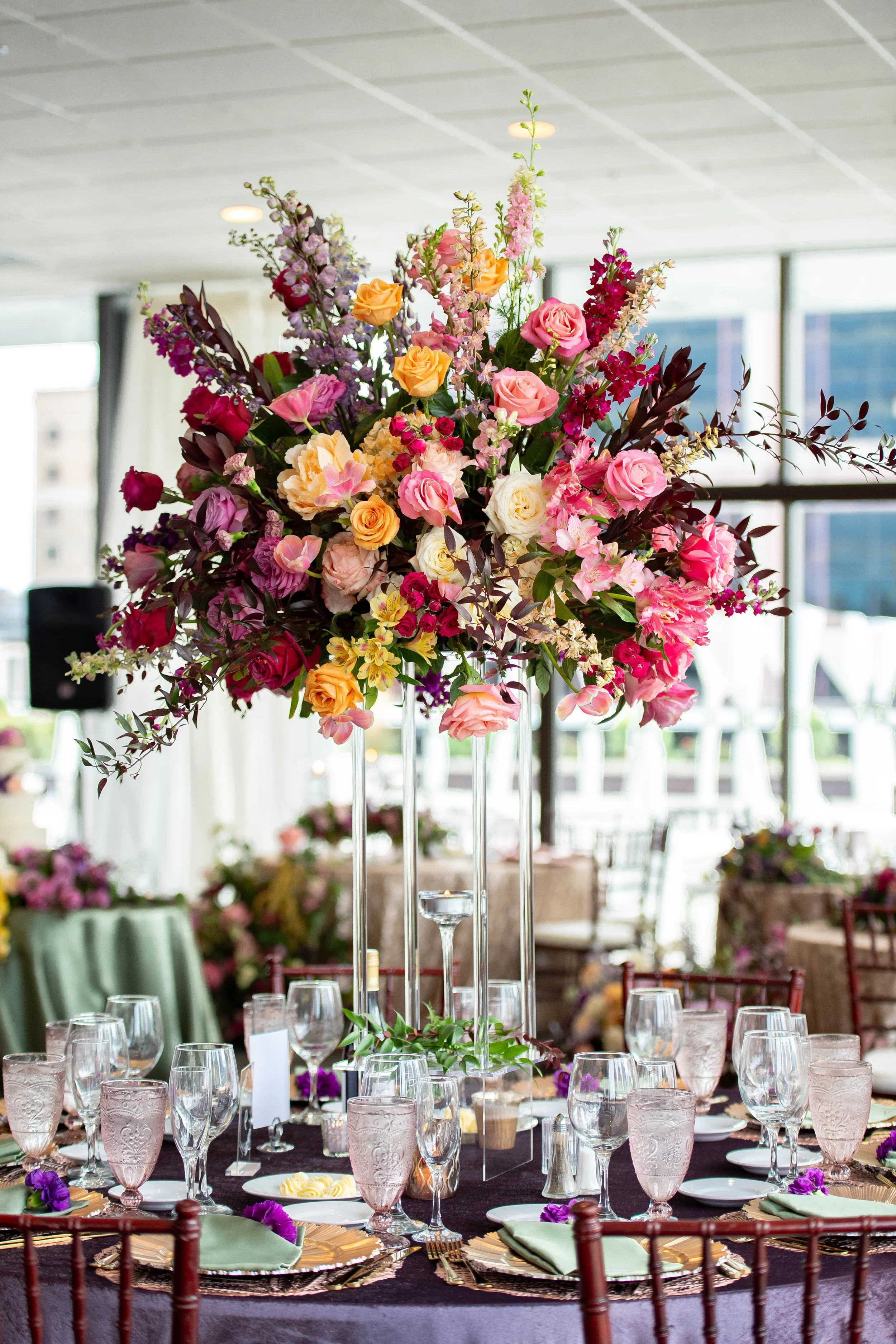 Elegant tablescape at JPS Events at Regions Tower featuring gold flatware, pink glassware, and an over-the-top multi-color floral centerpiece by our in-house florists at wholesale pricing. All-inclusive luxury wedding design in Indy.