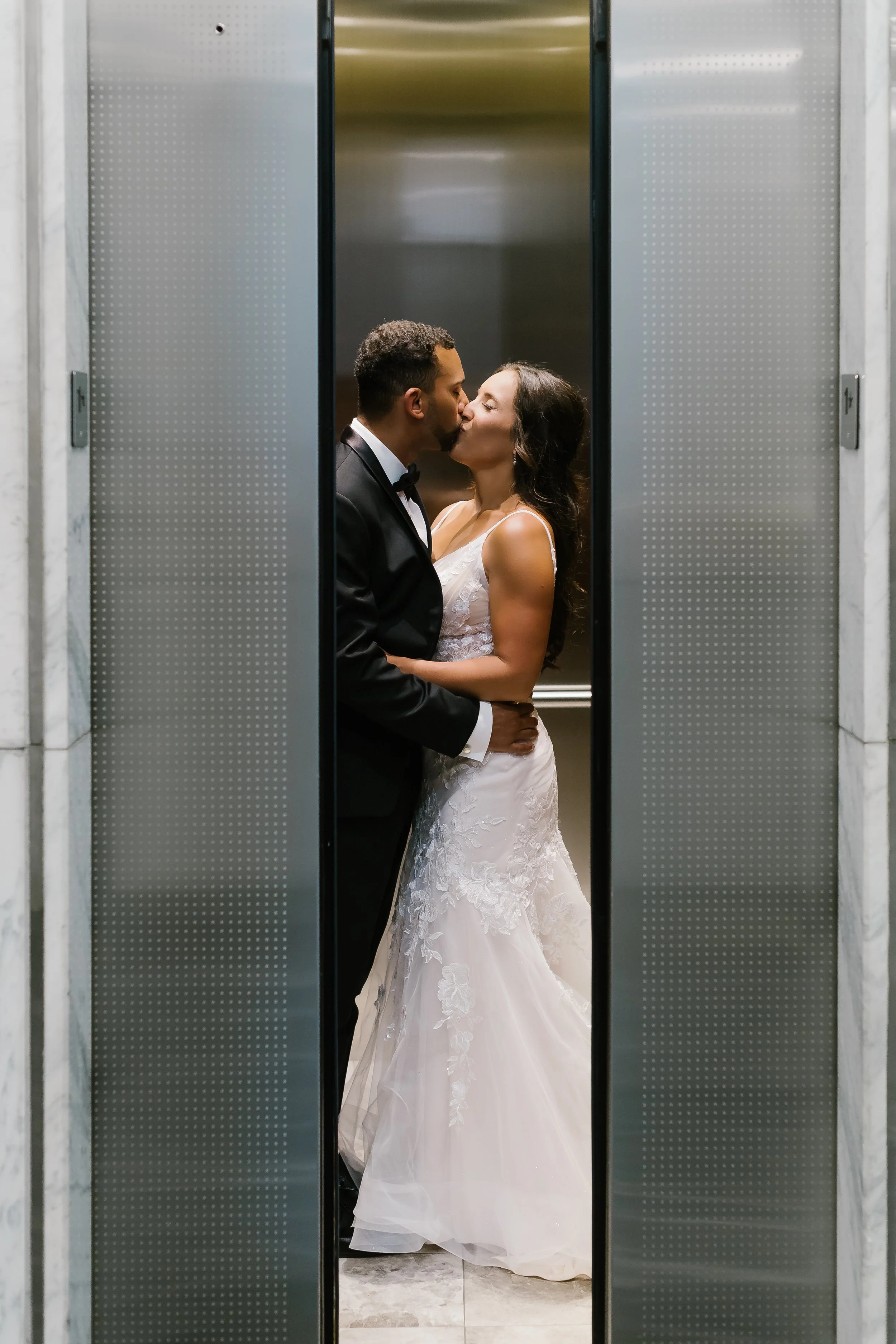 Romantic elevator kiss at JPS Events at Regions Tower. Highlights modern metropolitan chic architecture, private penthouse elevator access, & exclusive urban photo ops near Monument Circle in downtown Indy.