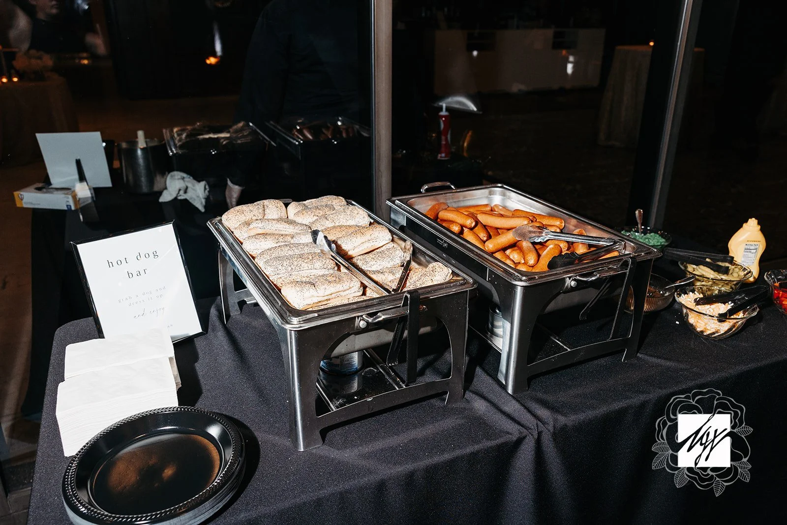 Buffet hot dog bar with buns, hot dogs, and condiments on a black table—imaginative takes on classic wedding food and late-night snacks by luxury in-house catering at JPS Events at Regions Tower in Downtown Indianapolis.